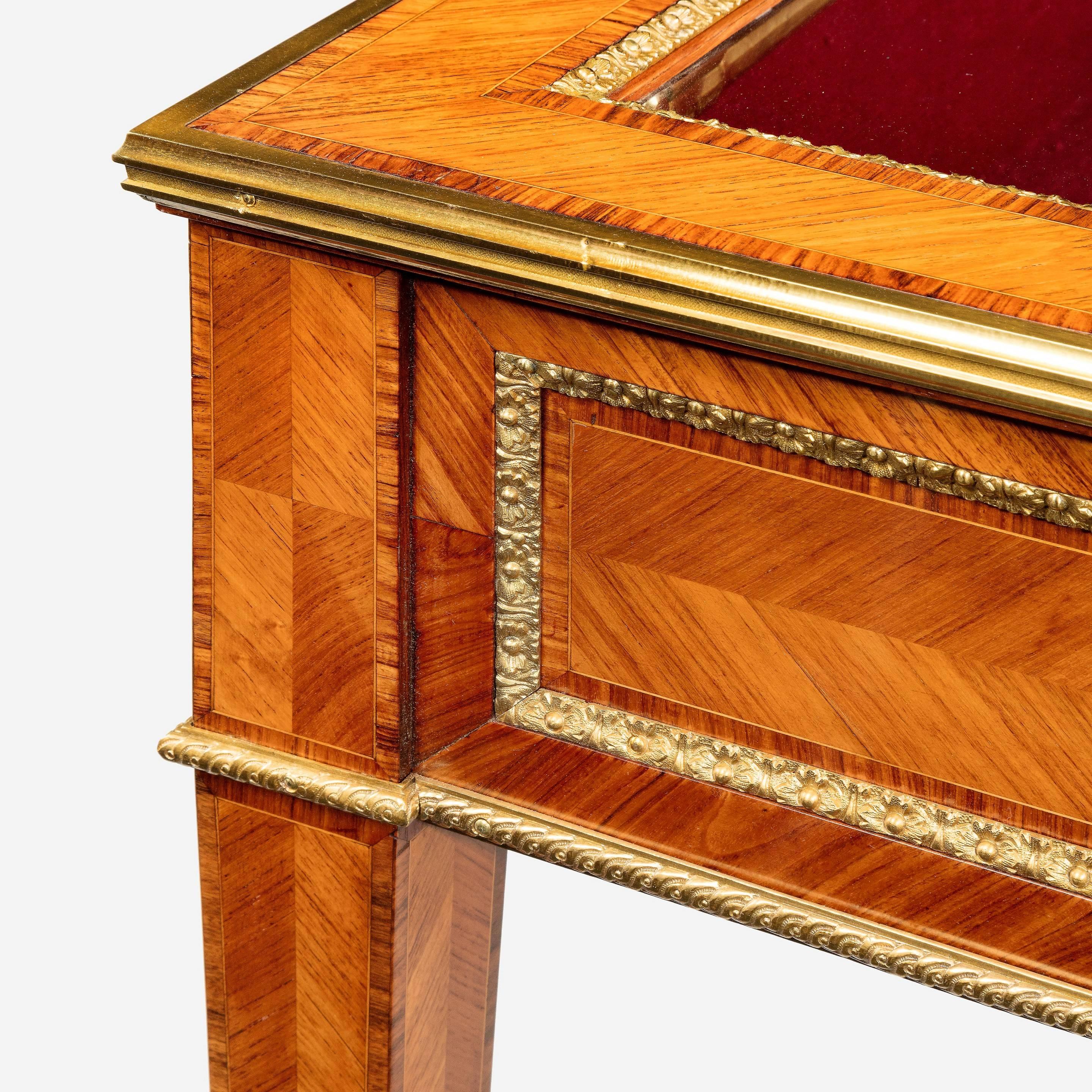 A matched pair of English Kingwood display tables in the French taste, each of rectangular form with slender tapering legs and glazed top, decorated with quarter veneers, tulipwood cross banding and superb quality ormolu mounts.