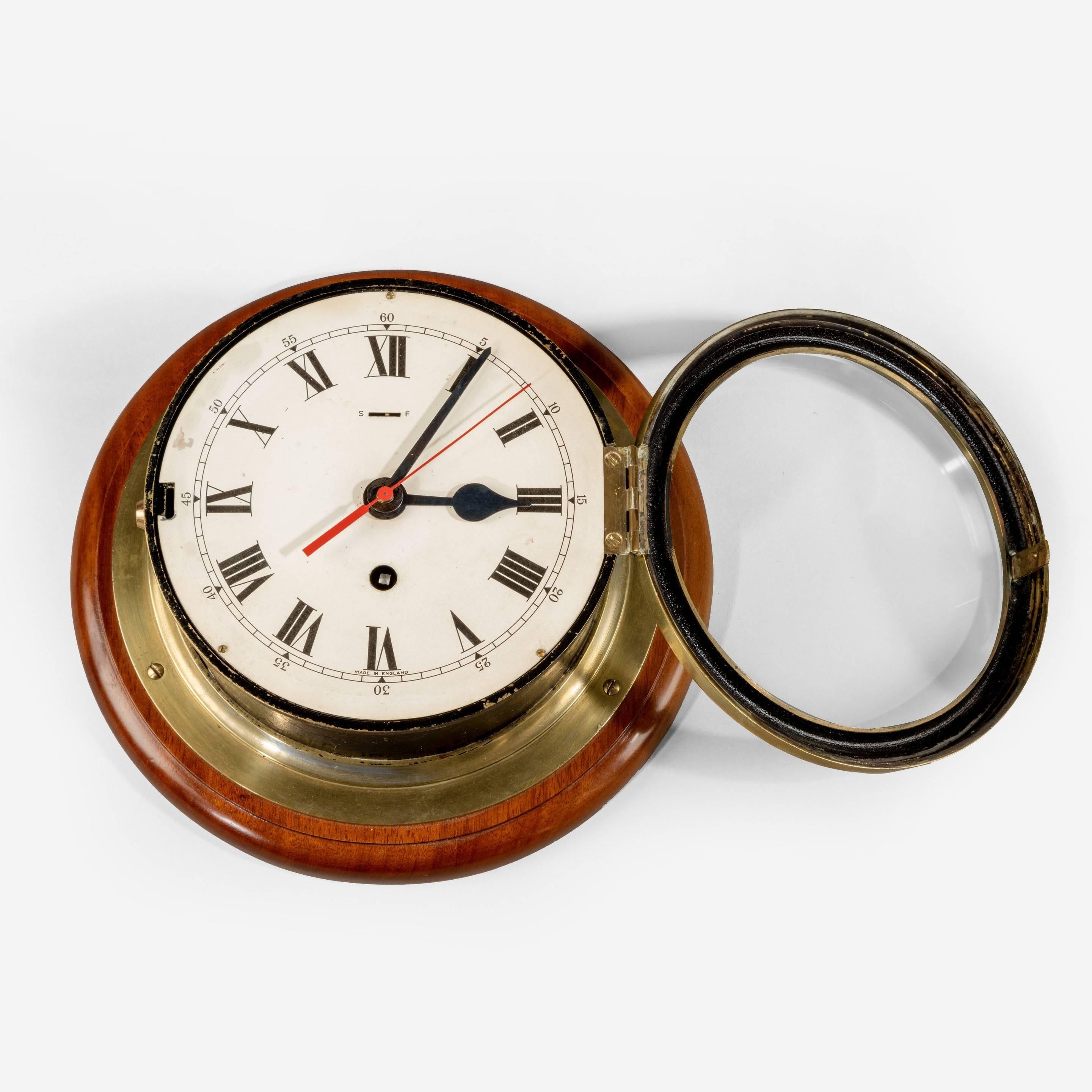 6 ½“ dial Smith’s Astral ship’s bulkhead clock with brass bezel and black body on a mahogany back-board.