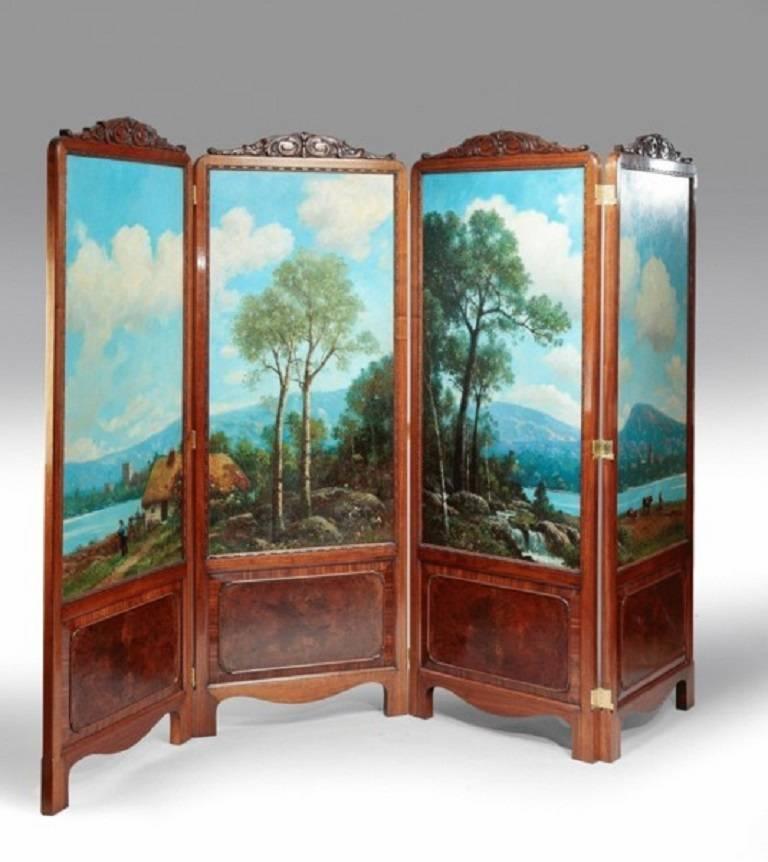 An unusual four fold screen with panels of oil painting showing a lakeside landscape within a walnut frame in the manner of Gillow.