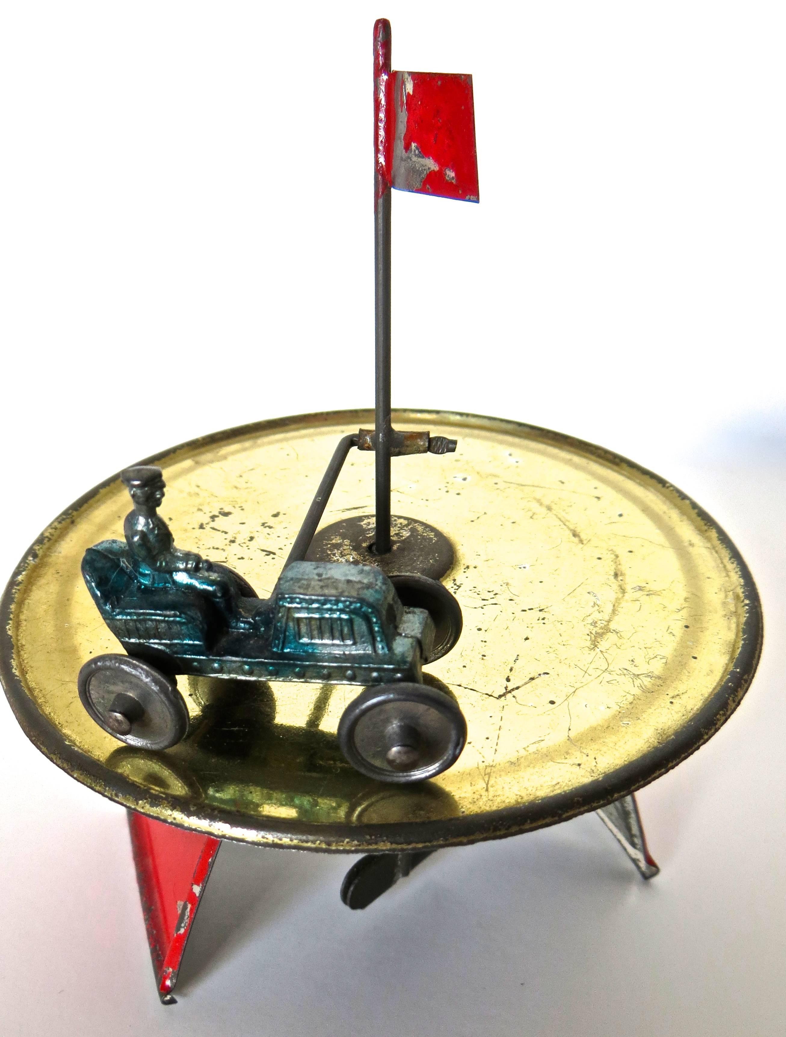 Upon winding up the mechanism underneath at the bottom of the toy, the old car will race around the track, as the circular sphere undulates, encouraging the car to continue. The toy is in remarkably excellent all original condition and paint,