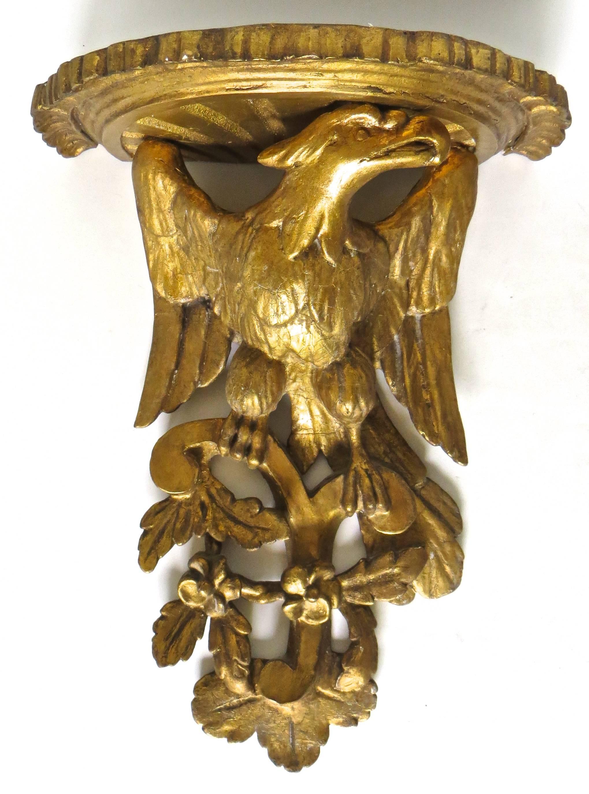 Late 18th century pair of English giltwood wall brackets; the molded top is supported by a winged eagle perched on a 