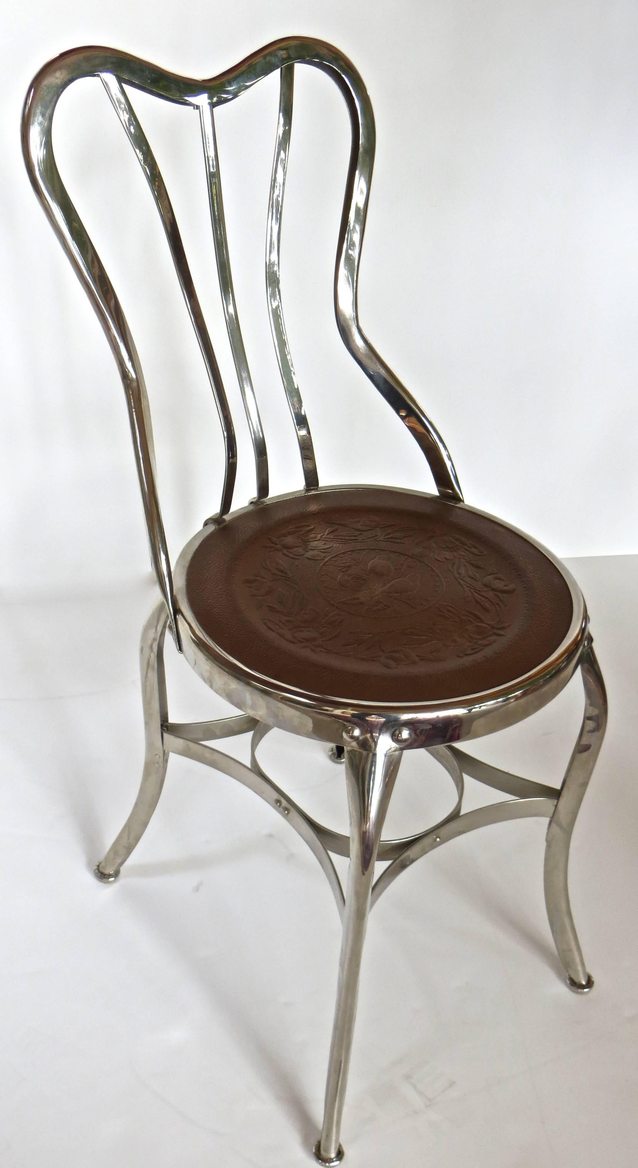 Amerikanische dreiteilige Eisdielengarnitur, bestehend aus einem Tisch und zwei Stühlen. Der Tisch hat drei Metallbeine aus Stahl, die in einem eisernen Kugel- und Klauenfuß enden, der eine runde weiße Marmorplatte trägt, die auf einem 1