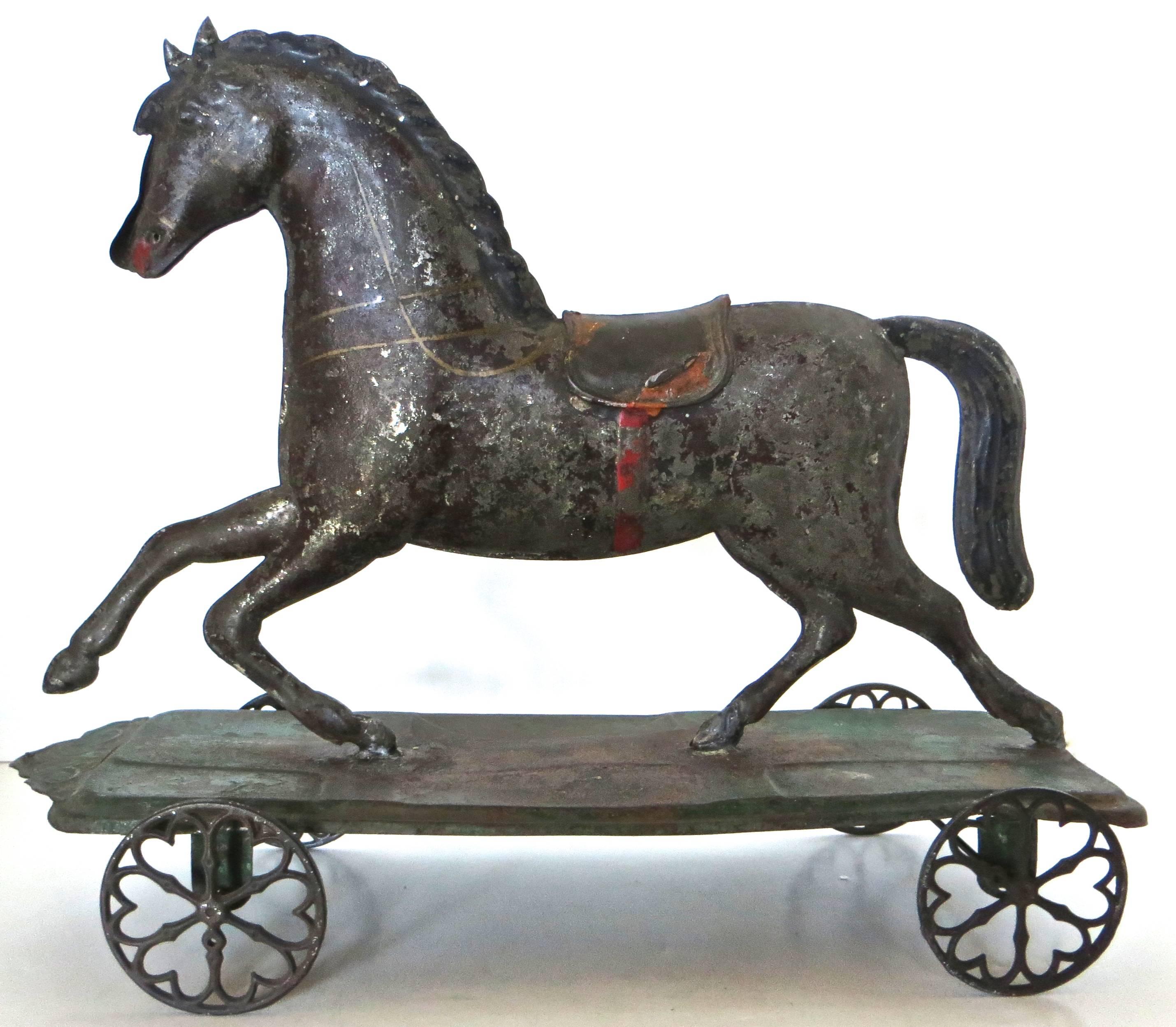 Toys of this nature would have been made for children to drag around the floor by a string (note the small hole in front of the platform), or pushed along and played with on the floor. This American tin platform horse pull toy (also referred to as a