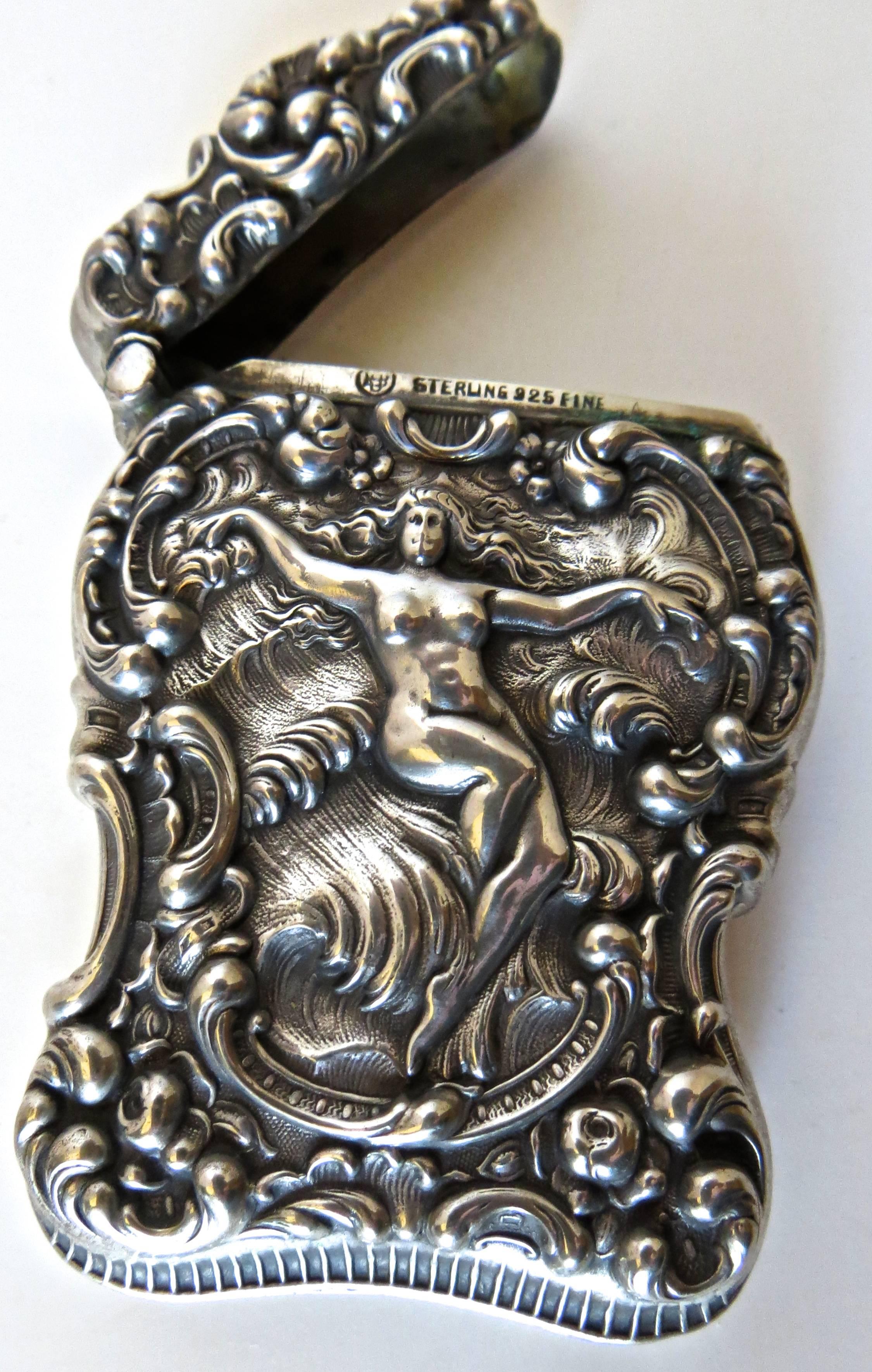 Listed is a quality Art Nouveau sterling silver match safe in repousse relief. It is typical of risque bar items used at the turn of the century, with a nude floating on a cloud as the central theme, and an elaborate floral design framing the