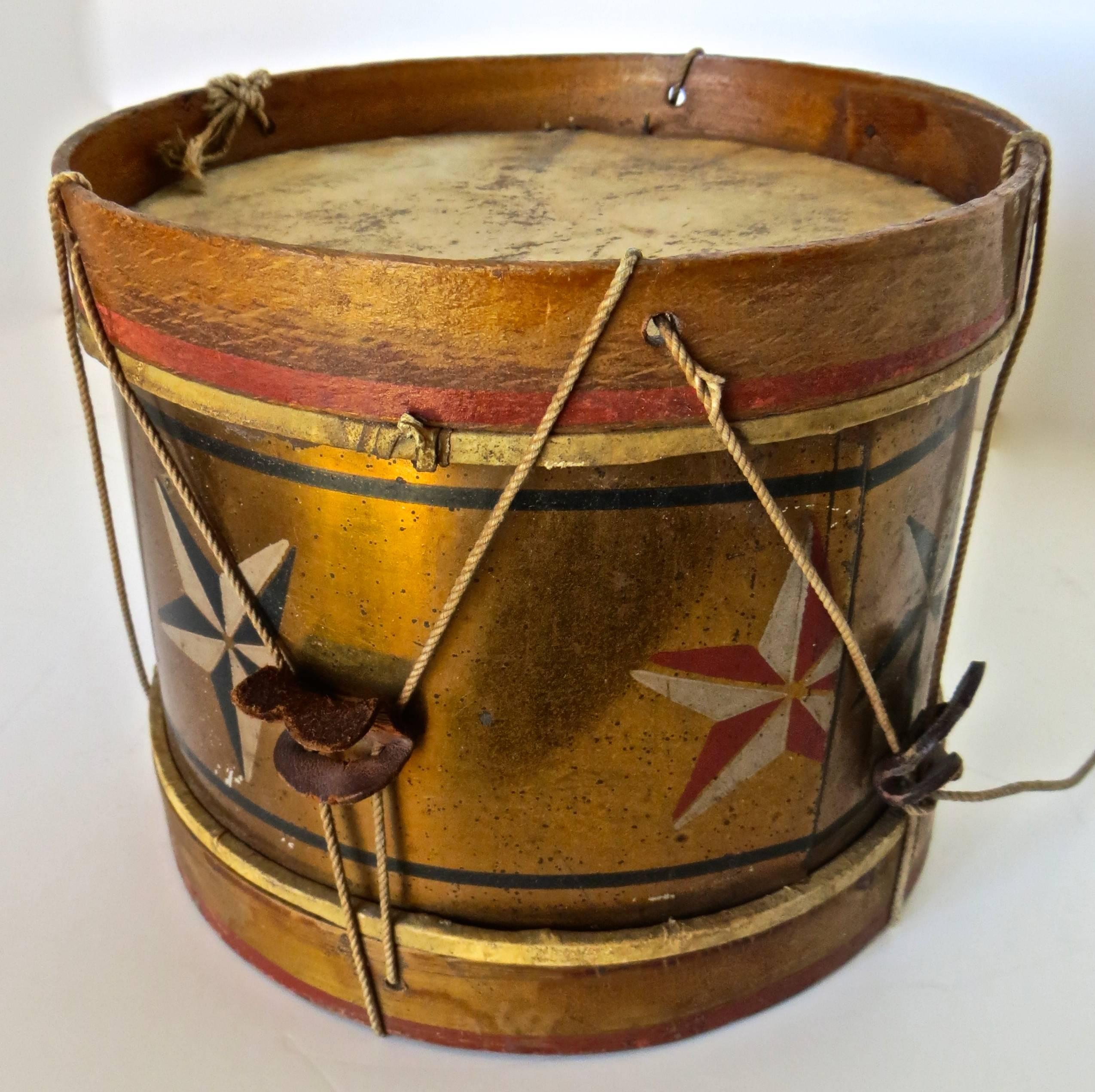 Wonderful folk art item and a reminiscent article of Americana consists of a child's toy drum with hand-painted decoration and a patriotic theme, with a pair of hand-painted American flags and stars around the perimeter along with two hand-painted