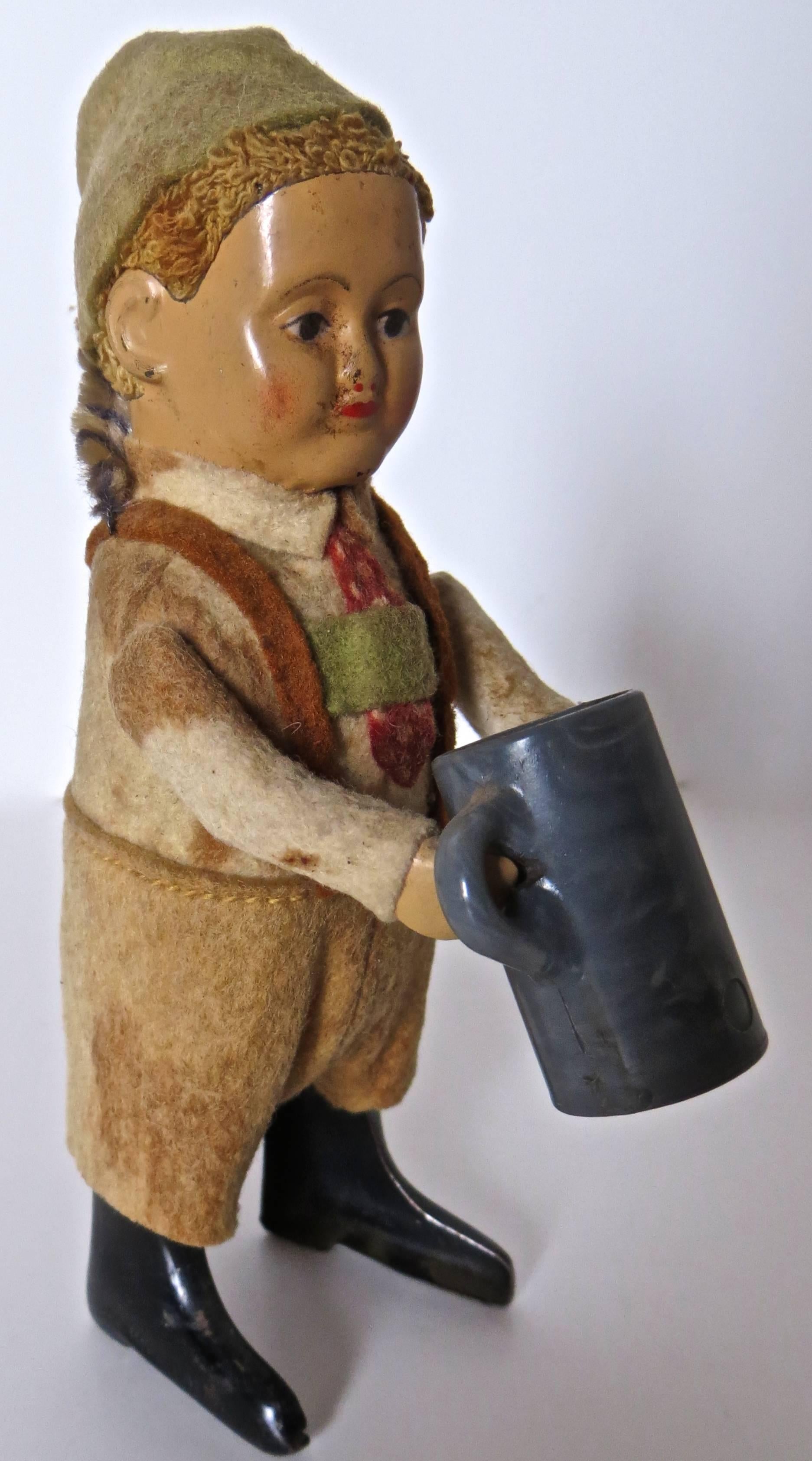 Entertaining clockwork toy that when wound up starts young German boy dancing and drinking from his beer mug. Near mint condition for this toy manufactured by the Schuco Company of Germany, circa 1940's. Hand painted metal face has a porcelain like