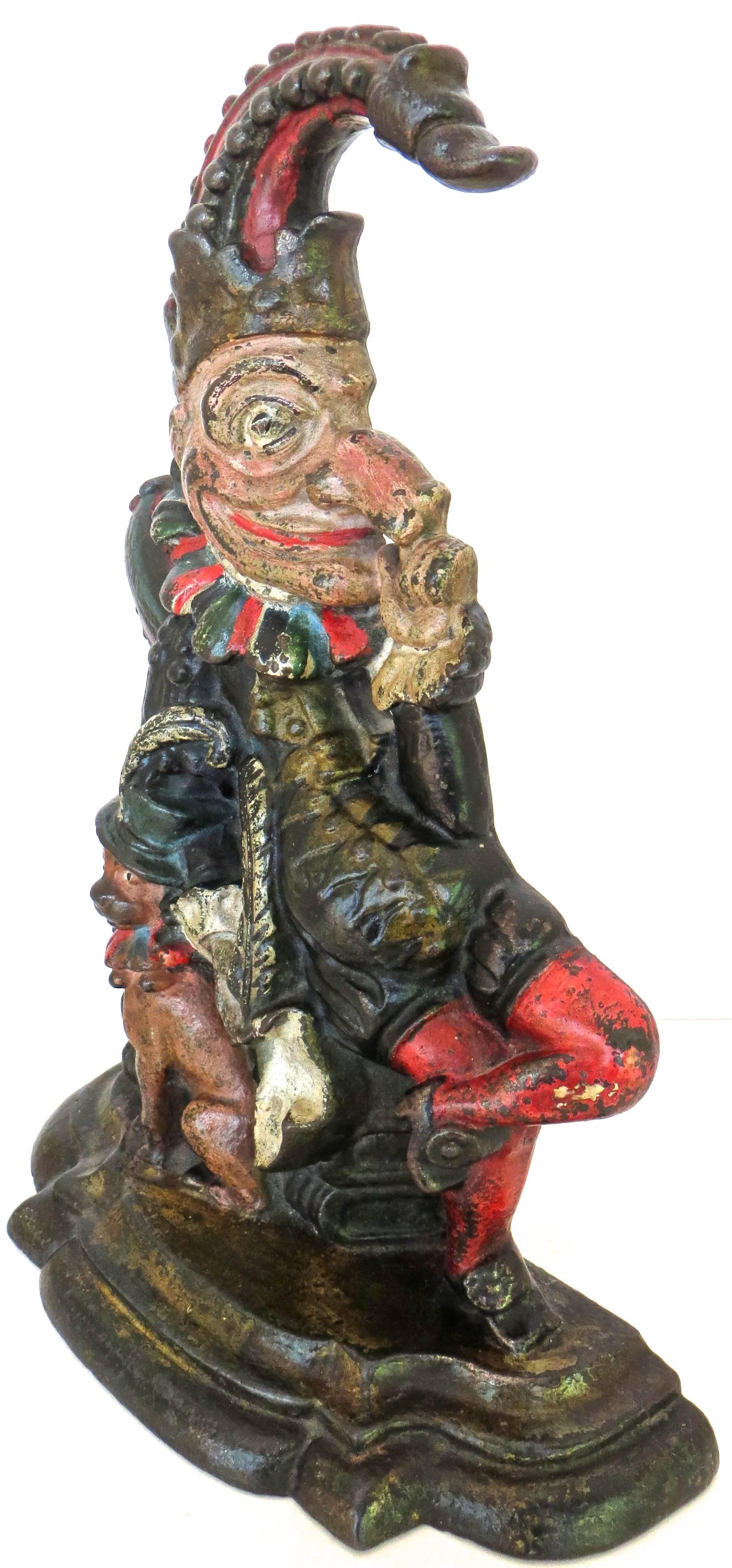 The subject matter depicts the proverbial 16th century stage character "Punch", of “Punch and Judy” notoriety. He is sitting on a stack of books with a dog (Toby) by his side. The finely detailed and intricate iron casting portrays