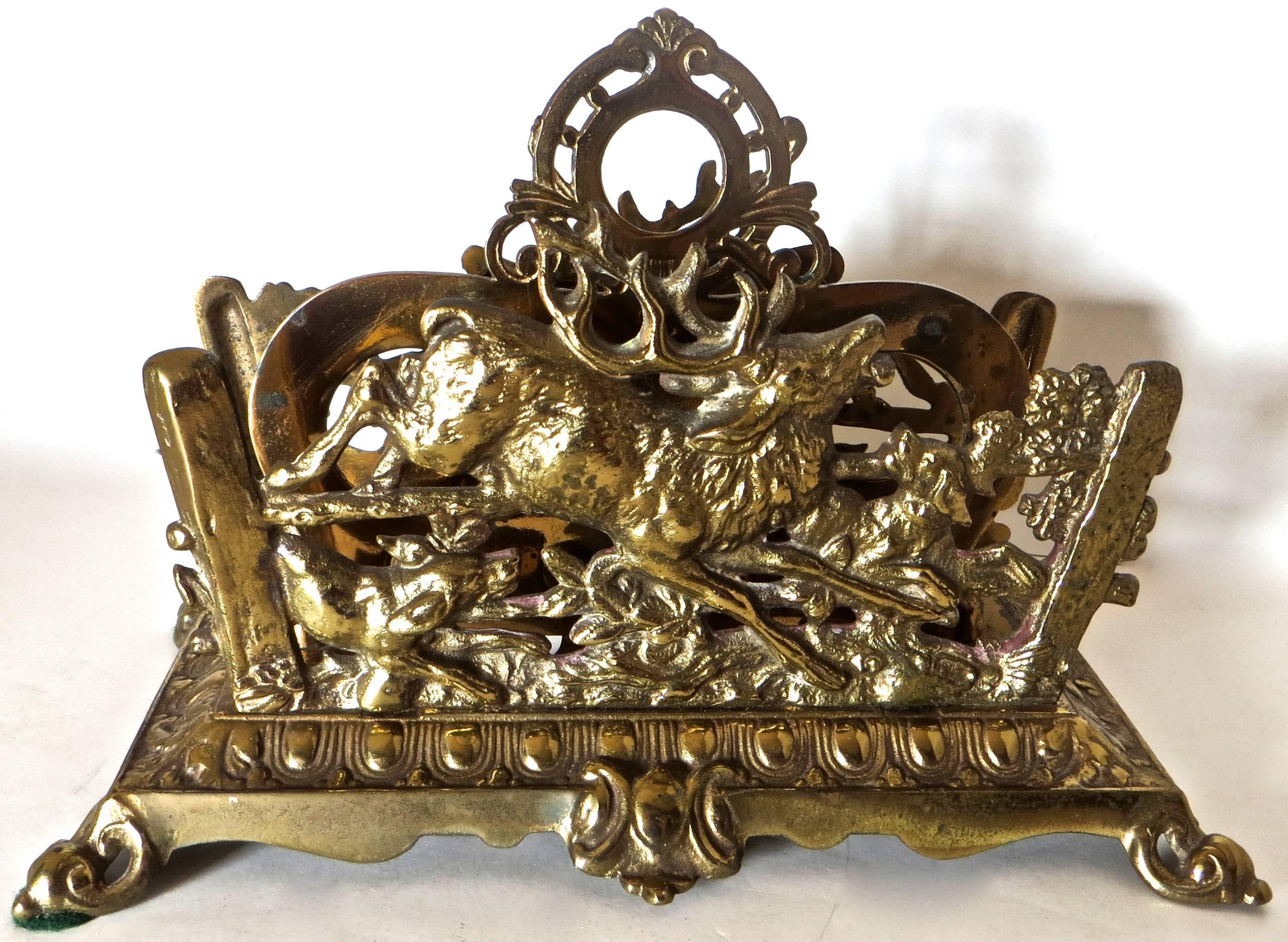 Brass-plated cast iron letter holder portraying a hunt scene with a deer and hunting dogs on each side of the two sectional desk piece with a decorative floral finial design. Fencing and foliage are also part of the design along with six decorative
