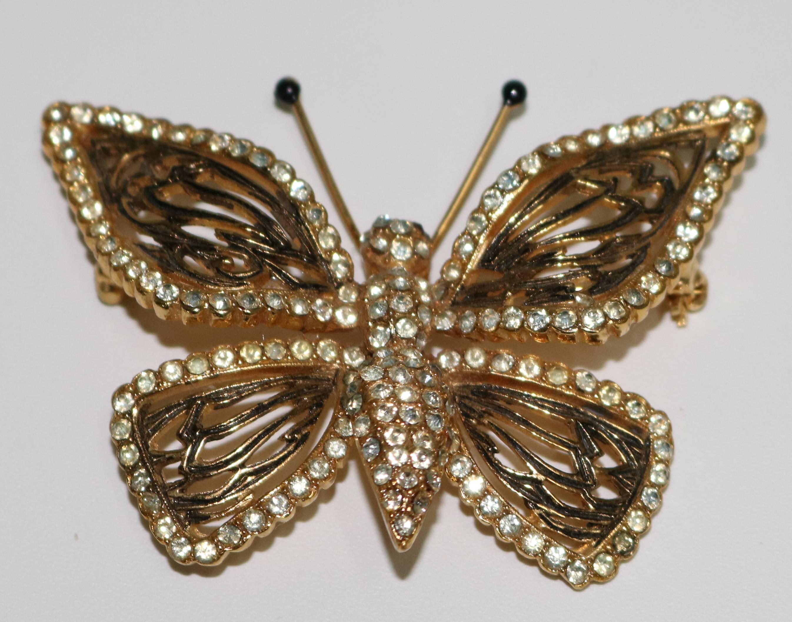 A lovely butterfly with diamante bordered wings and body in gold plate black enameled articulated wings and black stone topped antennae and red stone eyes. Marked en verso Vogue Jlry.

From the Edith Hale Harkness estate.