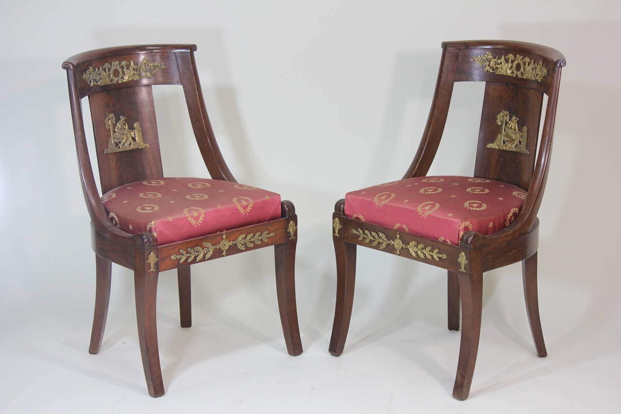 A important pair of finely figured carved flame mahogany, circa 1825,
girandole, chairs having finely cast and gilded elaborate bronze mount to the backsplat, curved crestrail, and seat rail depicting classical motifs with goddess on a stool,