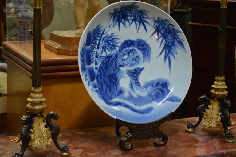 A Venerable Tiger fine large Japanese porcelain charger. A thickly potted porcelain charger with underglaze landscape decoration, a Venerable vigilant stylized tiger in landscape featuring graceful bamboo, unmarked. Stand not included.

Provenance: