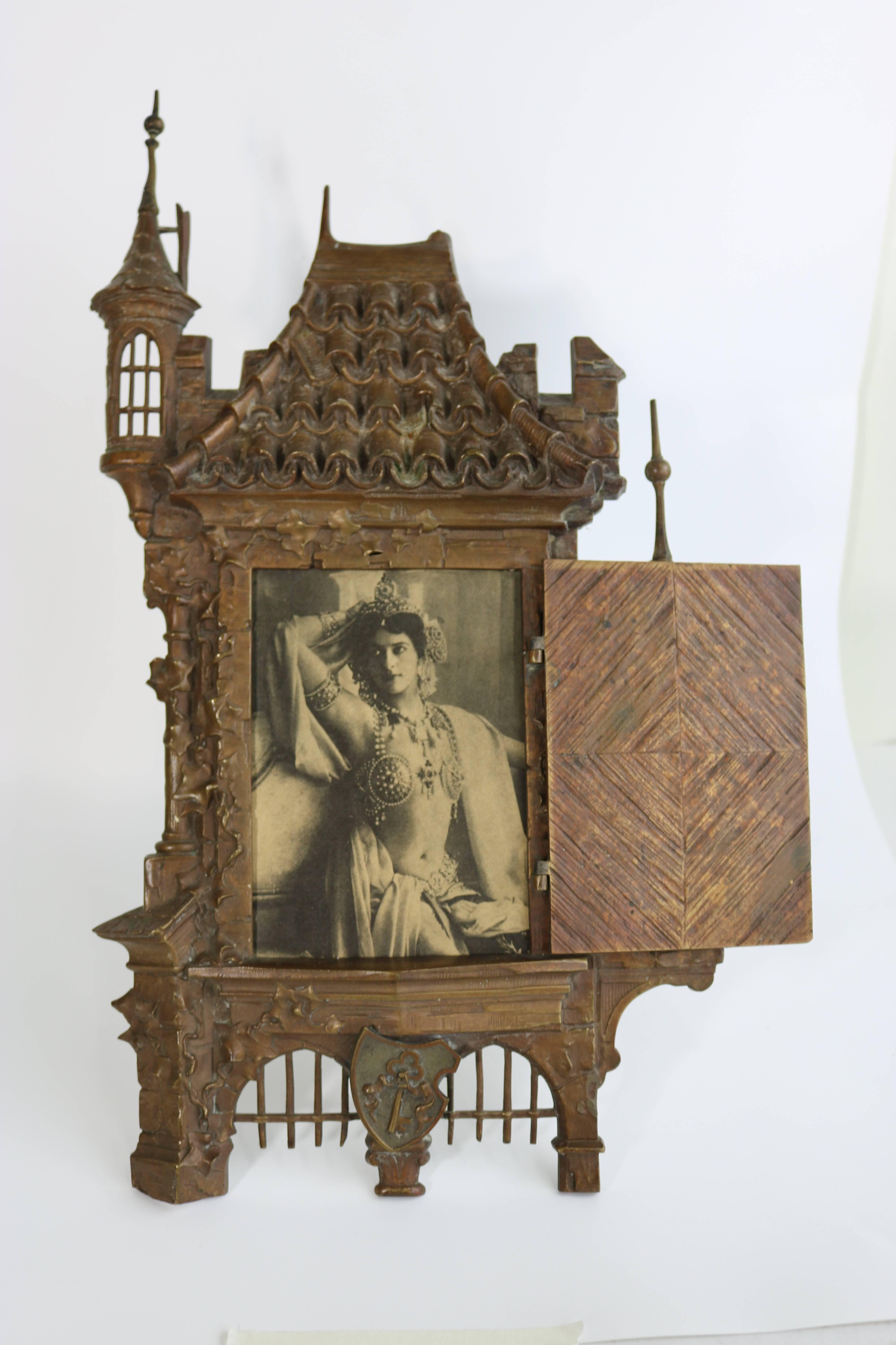 'Open Sesame', truly one-of-a-kind exotic large picture frame in an Arabian nights castle shape has an open and close door panel over the picture, a bronze metal finish. 
Photo size approximate 5.5