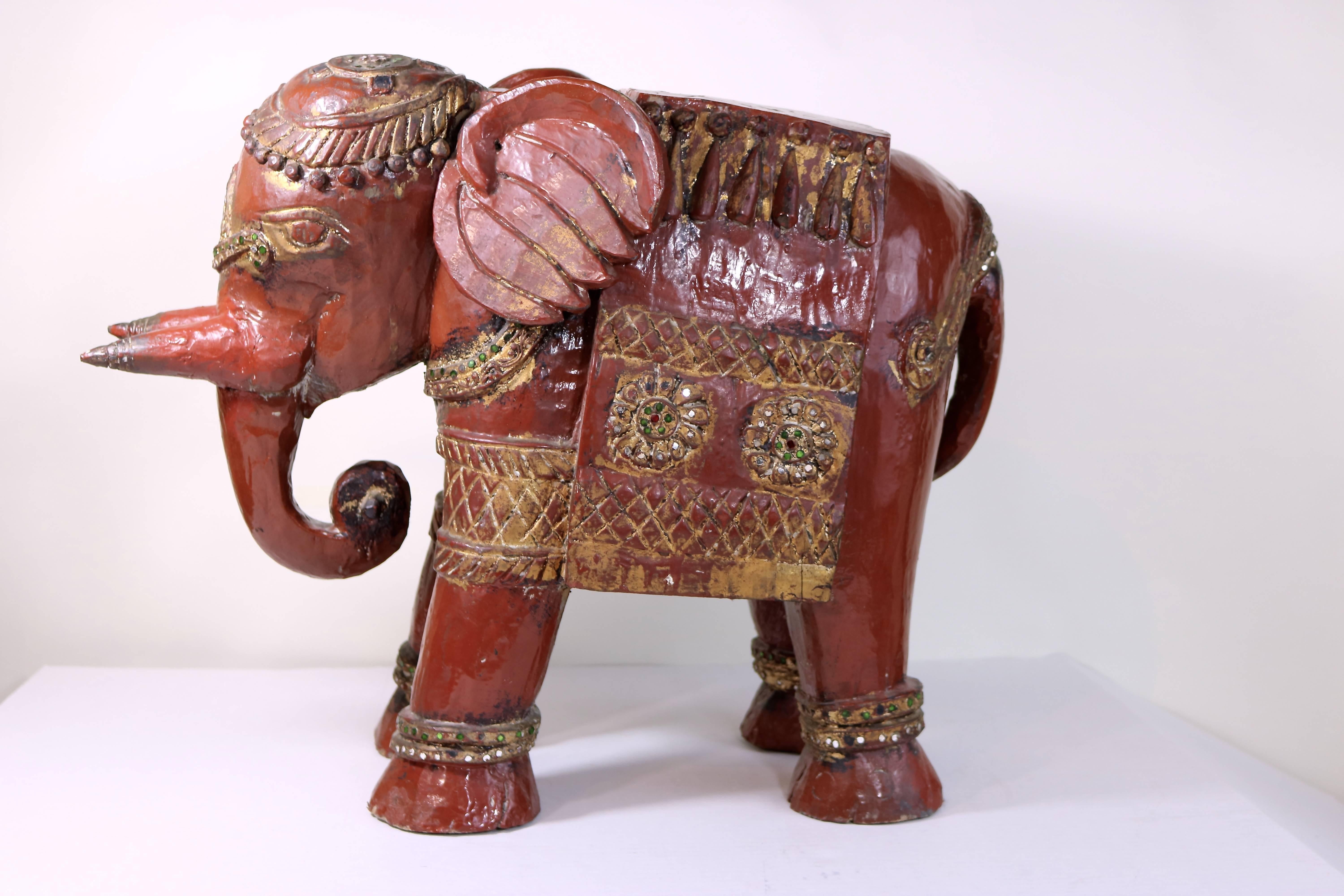 These are most enchanting pair of highly decorated rare elephant carvings of red oxbood lacquered teakwood! 
A late 19th century pair of teakwood lacquered oxblood color Anglo-Indian elephants with gilt carved trim and colored mirror inlays. Very