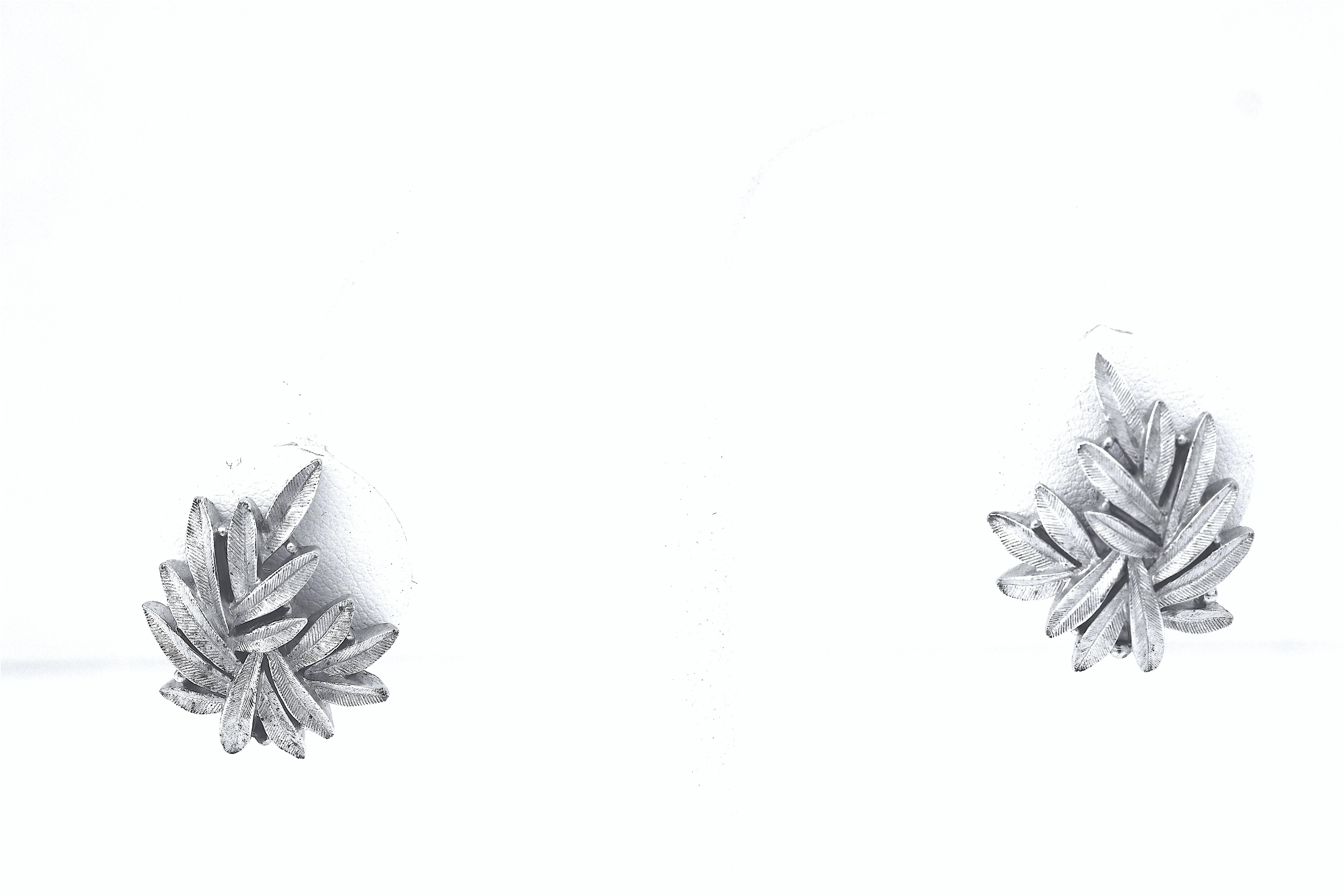 A brushed silver tone articulated leaf necklace and matching earrings by Trifari,
The delicate appearance of each asymmetrical leaf with a ribbed pattern design
has 10 linked panels on the necklace a chain for adjustability, a hook marked Trifari