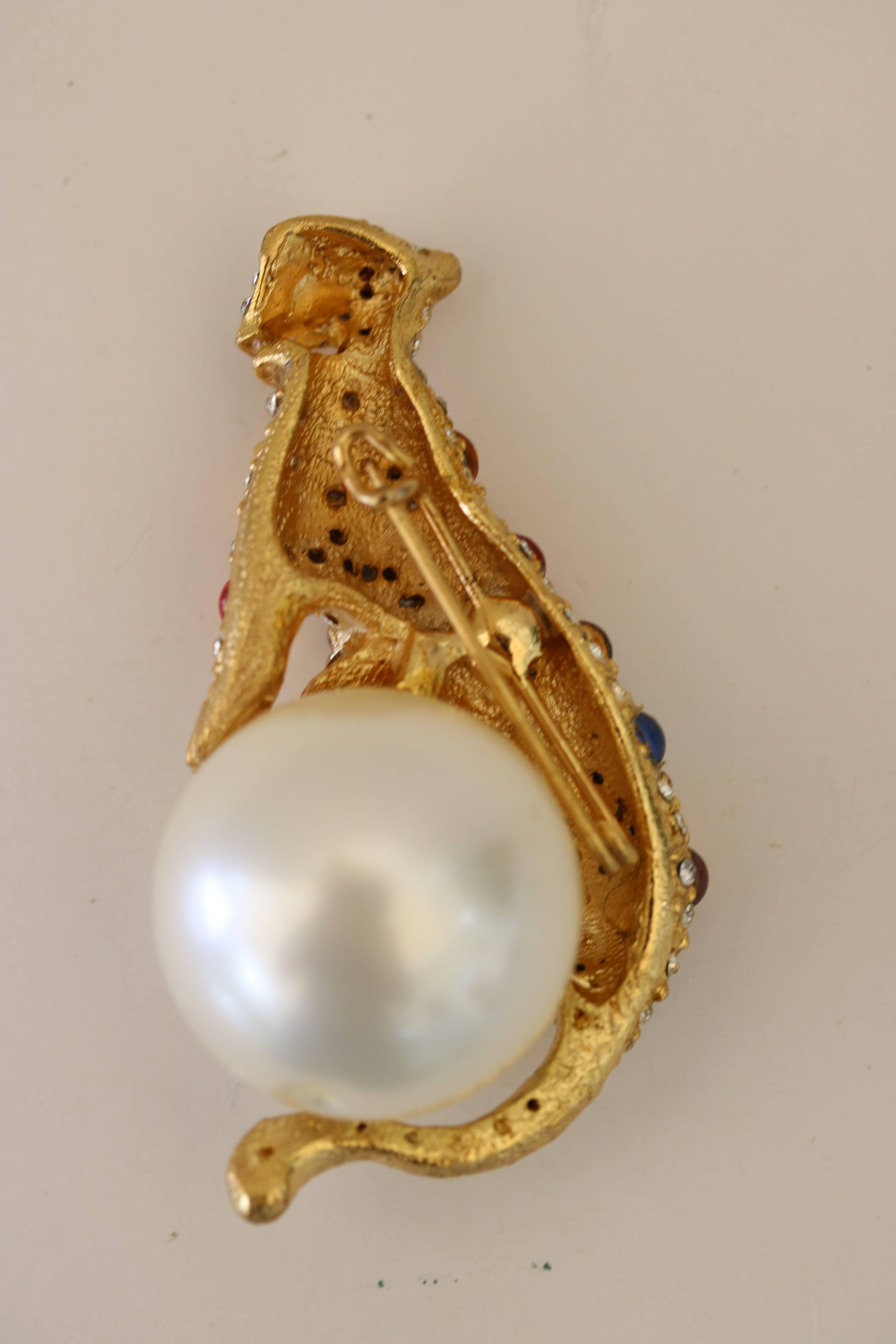 An iconic panther fashion gold tone brooch studded with multi-color glass cabochon stones as well as rhinestones embellish a stylized panther atop a huge faux pearl cabochon.  REDUCED FROM $895. TO $595.
 In the luxe taste of the model designed by