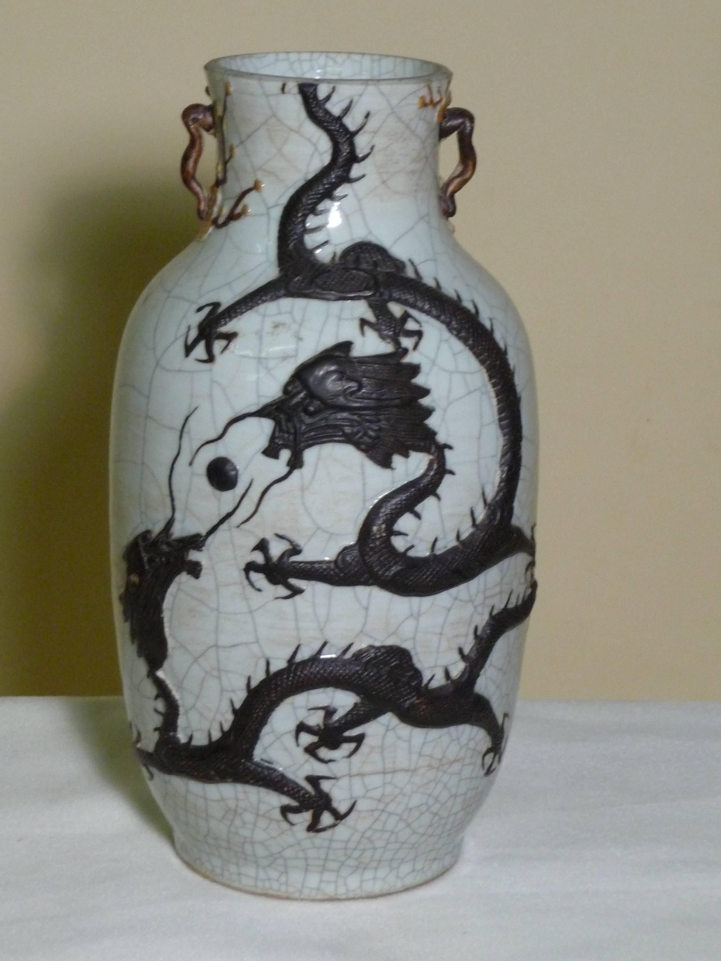 Chinese Qing Dynasty large baluster form stoneware vase, celadon crackle glaze finish with high relief iron stained clawed dragons, and crane. Small handles with plum blossoms enhanced with enamels-late 19th century.  

Guangxu period-1875-1908