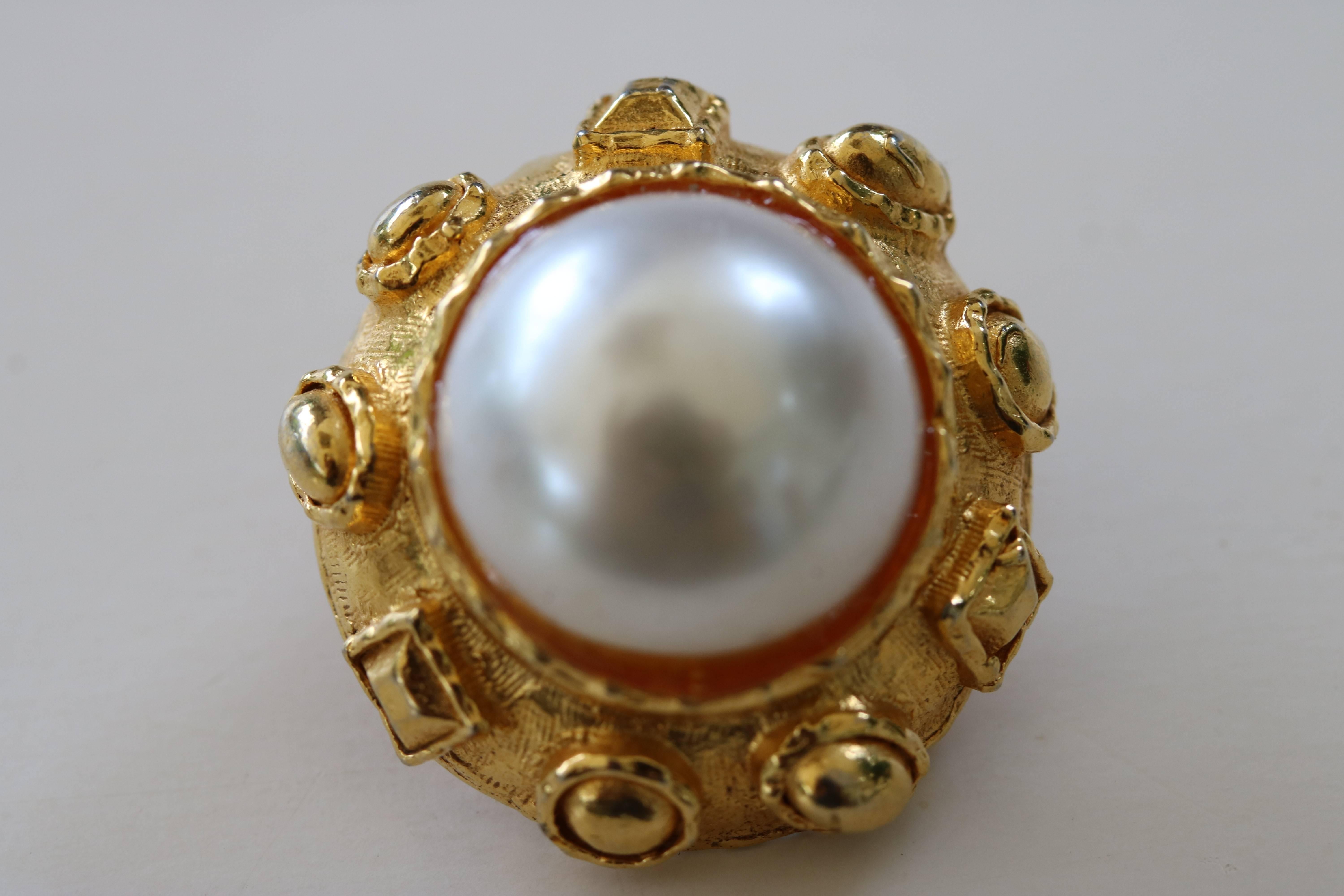 Early 1980s Chic faux pearl and heavy gold plate earrings. in the refined taste of Coco Chanel,
Large center faux pearl surrounded by heavy gold plate with designer decorative border.    unmarked clip ons.

 We have much more jewelry to offer-see
