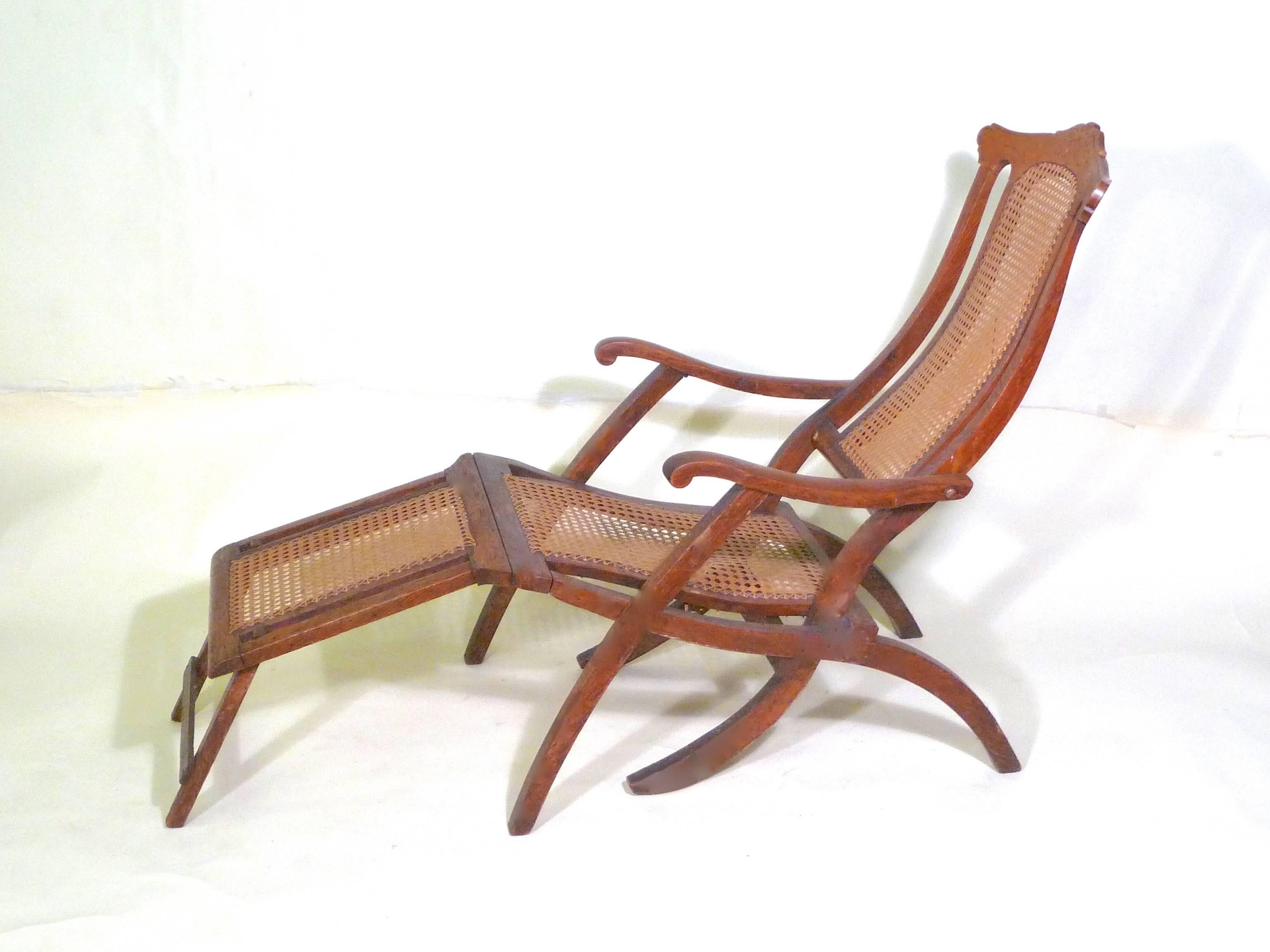 Late Victorian/Edwardian traveling on the great steamer ships of that era would have been enlivened by time spent on deck in one of these steamer chairs. Made of a hardwood, probably mahogany, and traditional caning, an articulated Victorian back,