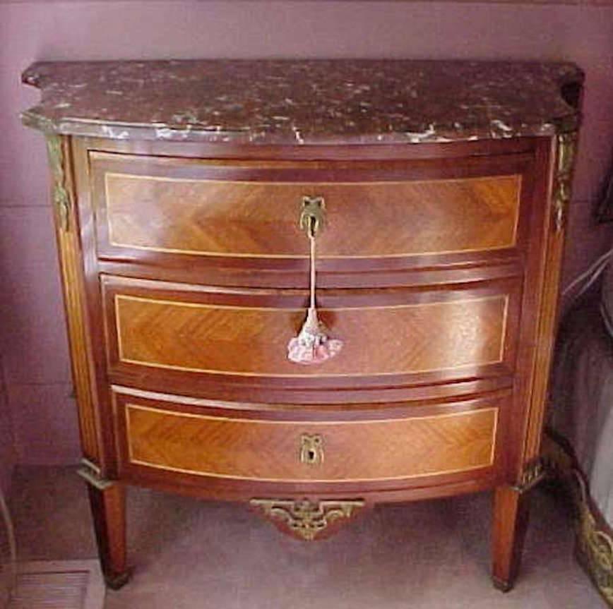 A refined French Louis XV style in perfect scale, three-drawer serpentine front chest with parquetry inlay kingwood and satinwood veneers with a period rouge marble top. Wonderful gilt ormolu bronze mounts and key locks with three drawers resting on