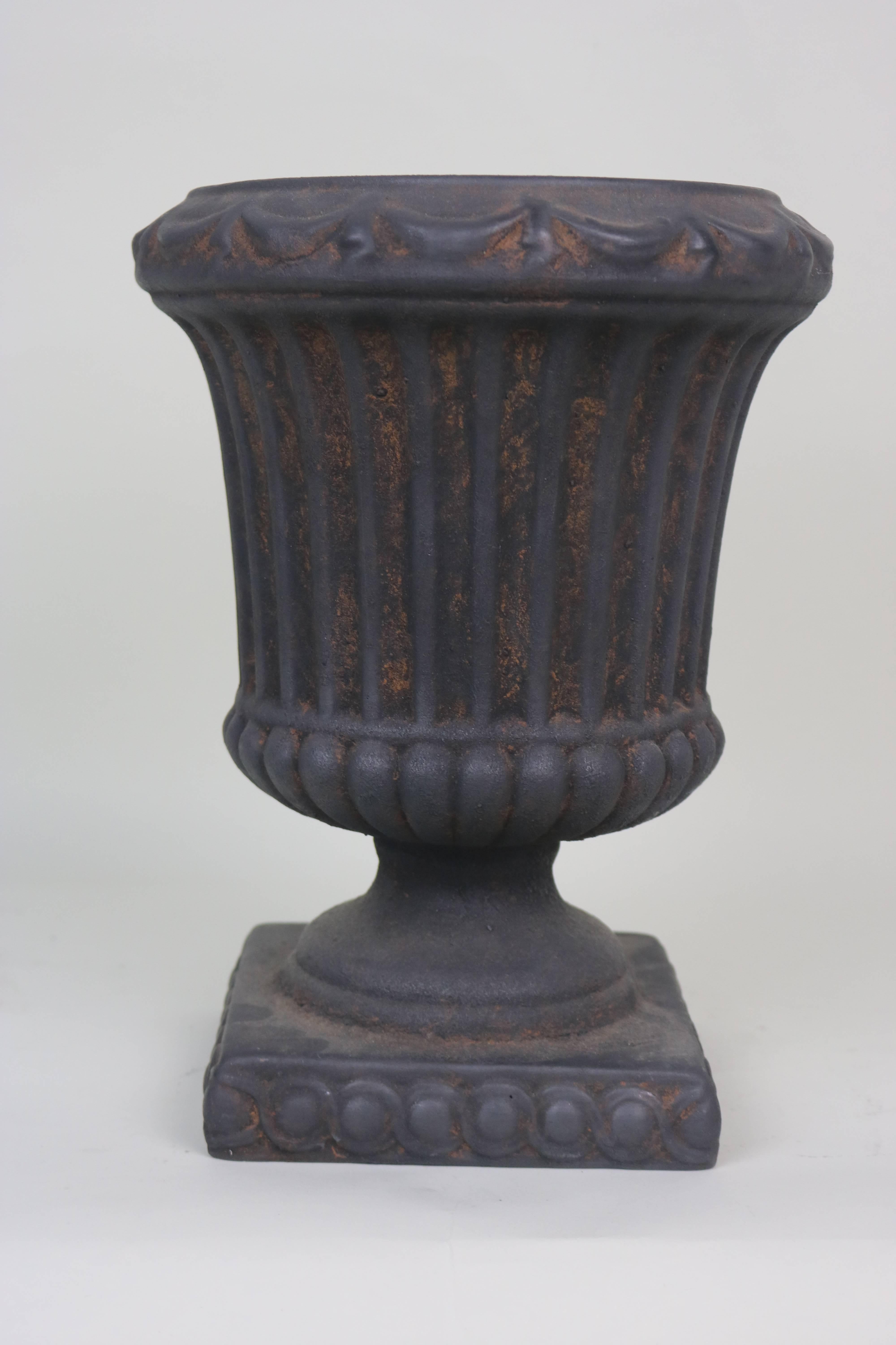 A distinctive high style terra cotta matte black urn planter with slight rusticated old world look, jardinière, planter, with classical patterns nicely articulated-fluted, ribbon top border, guilloche trim base. 
A decorative urn for decor with