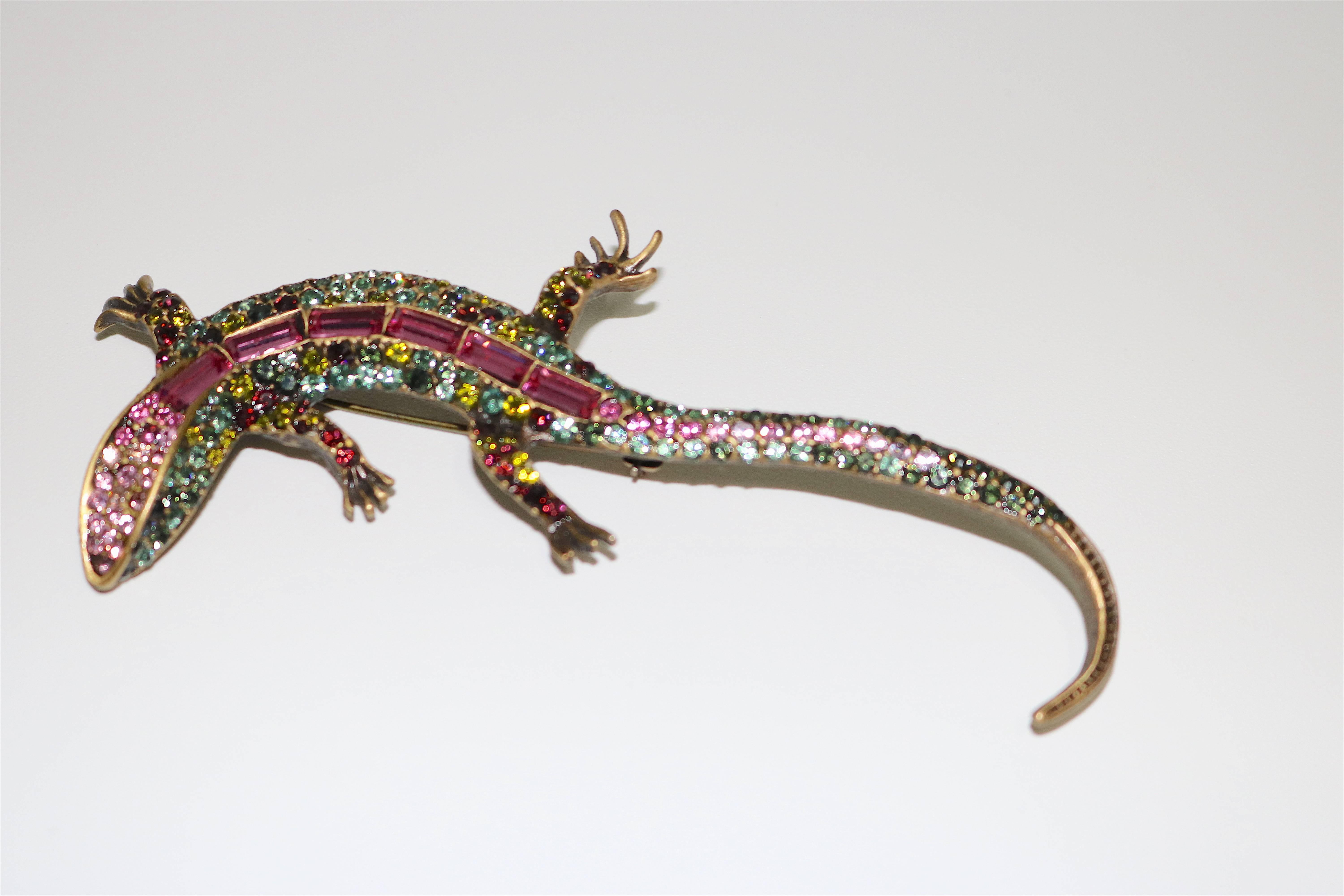 This beautiful Jay Strongwater salamander brooch has a gold toned base set with green, yellow, ruby and pink Swarovski® crystals including the top of it’s back is inlaid with large emerald cut pink crystals. It makes a gorgeous statement. The pin