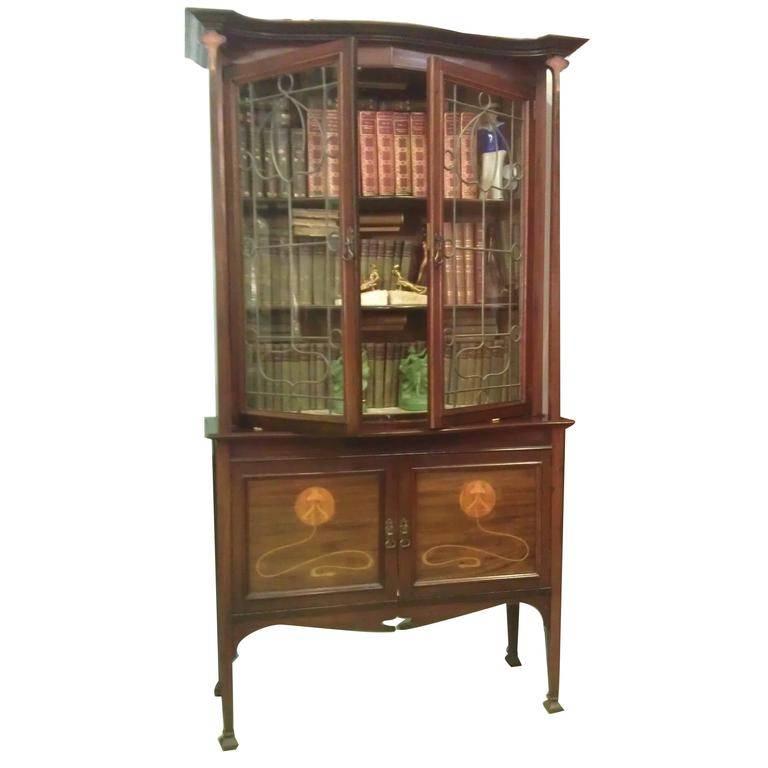 Exquisite Galle/Majorelle style fine example of Art Nouveau mahogany cabinet with gracefully tapered columns terminating in stylized marquetry flora capitals under a stepped overhang pediment. The columns flank the pair of leaded clear glass doors