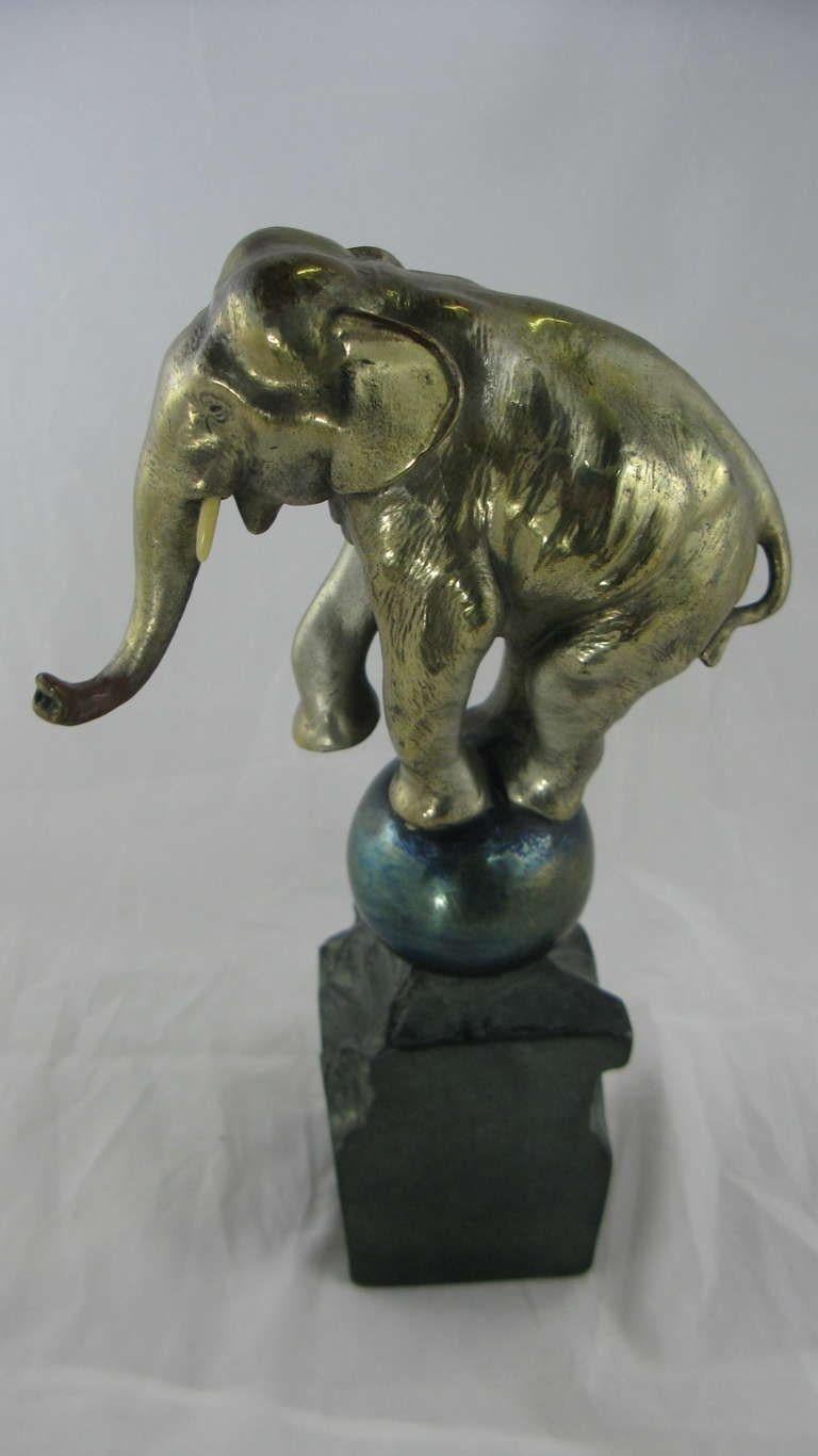 Art Deco whimsical silver plated bronze dancing elephant balancing on a blue glazed bronze ball and black patinated matte black bronze rock. A very unique image, beautifully detailed and a beloved object. Everyone in our family wants to keep this
