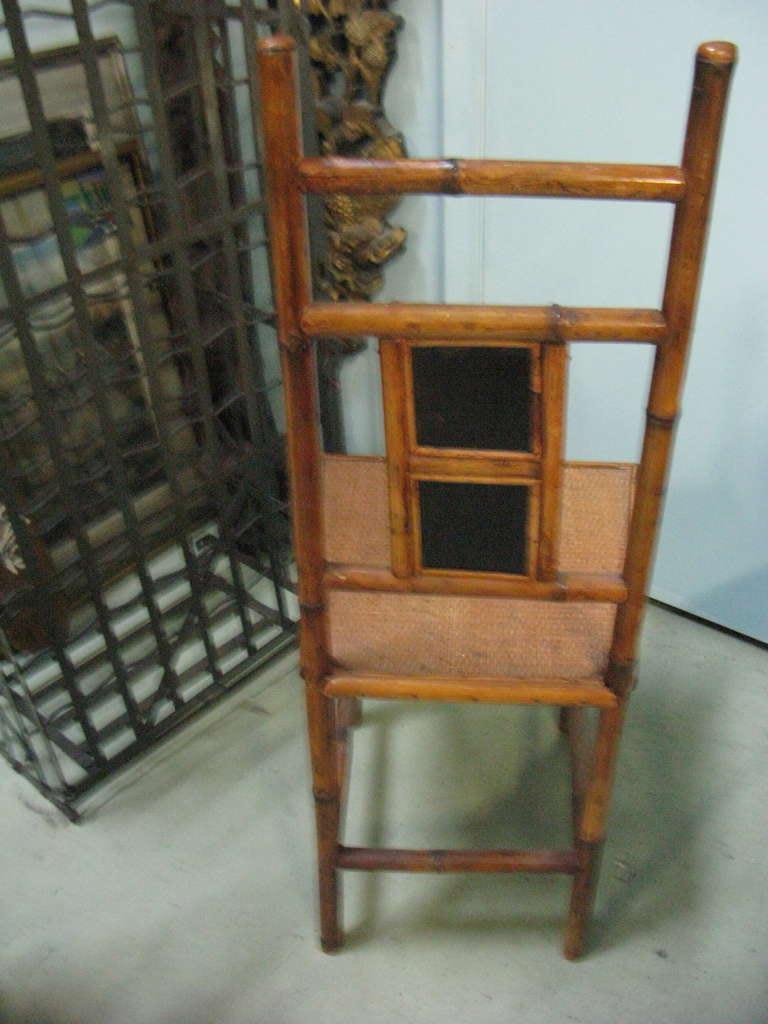 19th century rare pair of exquisite bamboo chairs with beautiful chinoiserie finely hand painted double inset panels with a peacock with fauna and a butterfly with flora. black lacquer double inset panels on the rear back. The bamboo is a lovely