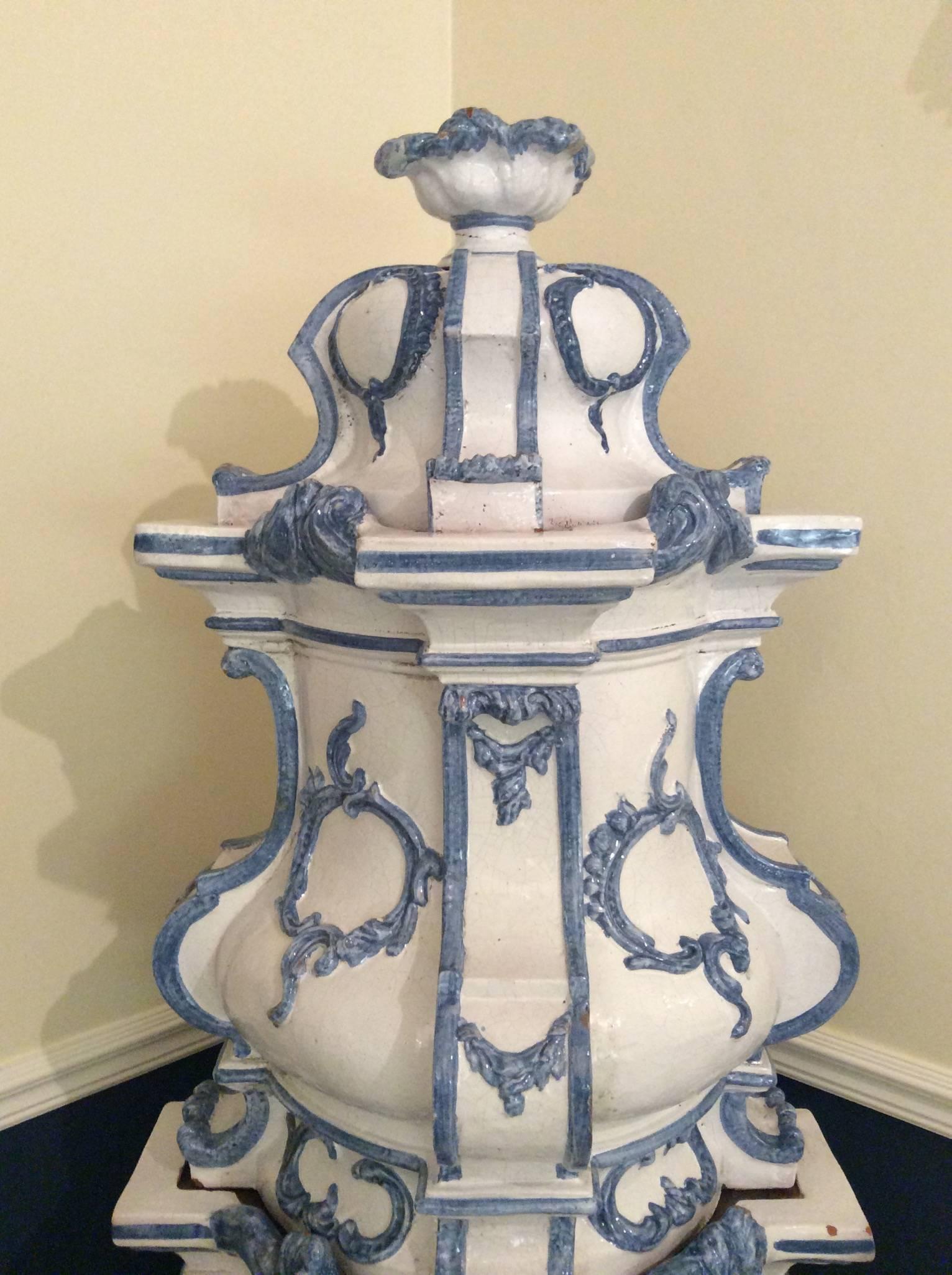 A large late 19th century South German or Austrian majolica-faience stove or kachelofen in the Rococo style.
Built in nine sections of typical Bombe format, fired in white with light blue floral decoration, complete with iron firebox door and
