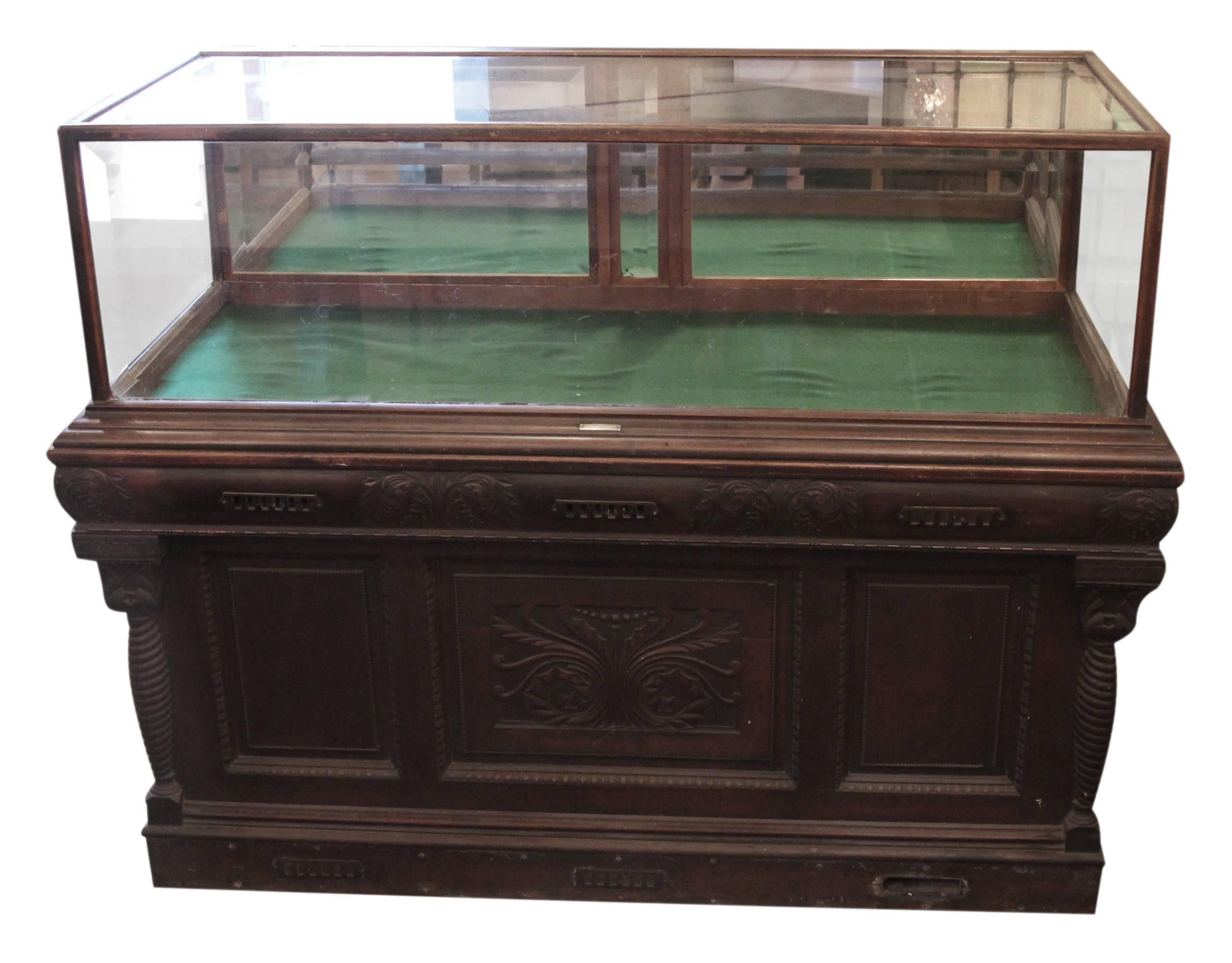 1800s carved oak framed cigar humidor with oak glass showcase on top by Whitcomb Cabinet Co. Features beveled glass with two pull down mirrored doors. The base is the humidor, and the brass vents are on the front and back. There are drawers and