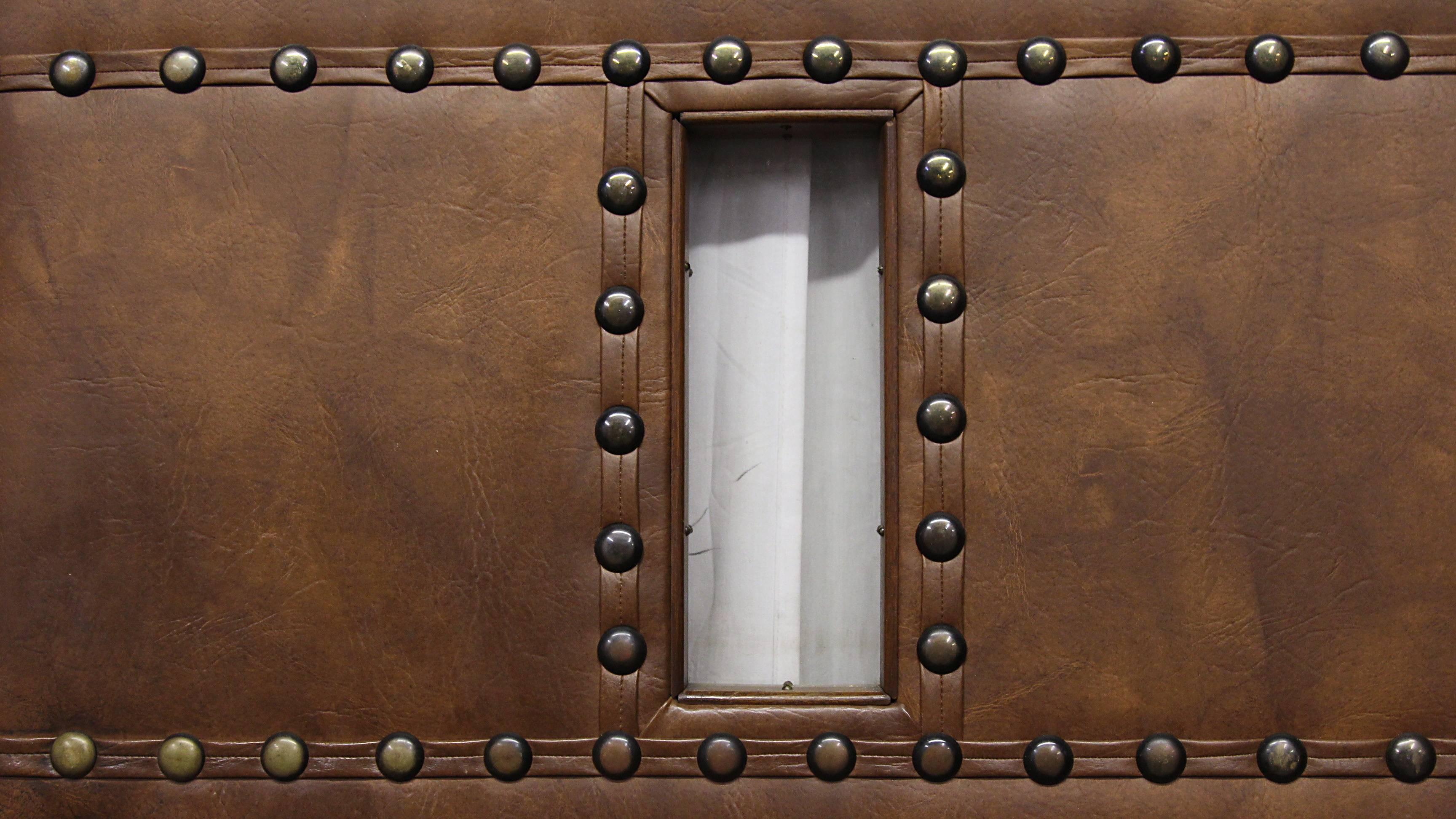 1940s leather like studded swinging door with original hardware including push and kick plates and window. This can be seen at our 400 Gilligan St location in Scranton, PA.