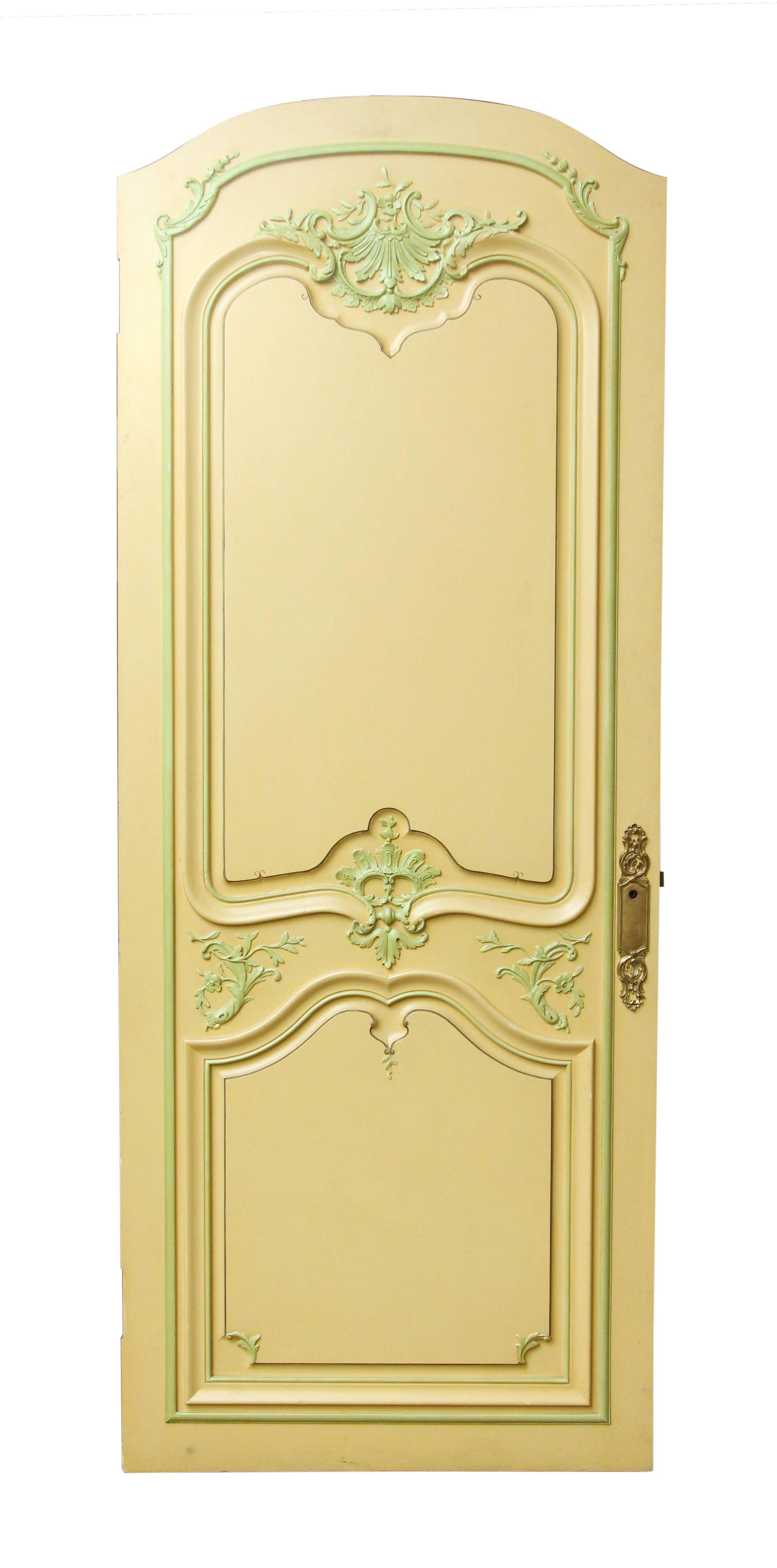 Three cream colored carved wood doors with green floral decorative designs along the panels. Features original decorative back plates attached. One pair and one single available. The single door is plain and white on the opposite side. Priced as a