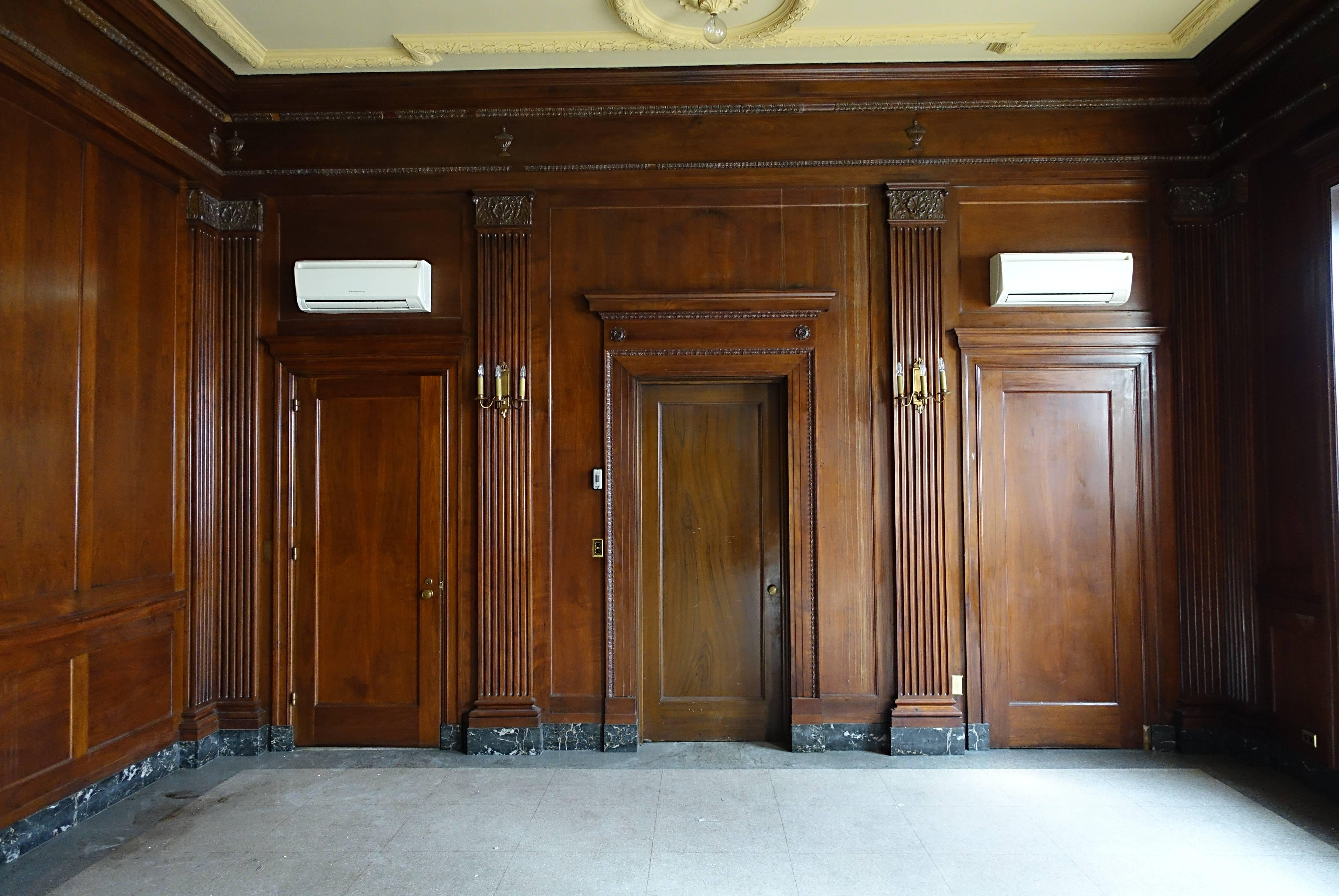 Solid walnut panels from the negotiating room of the prominent Williamsburg Savings Bank in Brooklyn, New York. The neoclassical building was erected in 1928. The room has one longer side with full panelling divided by four ornate fluted pilasters.