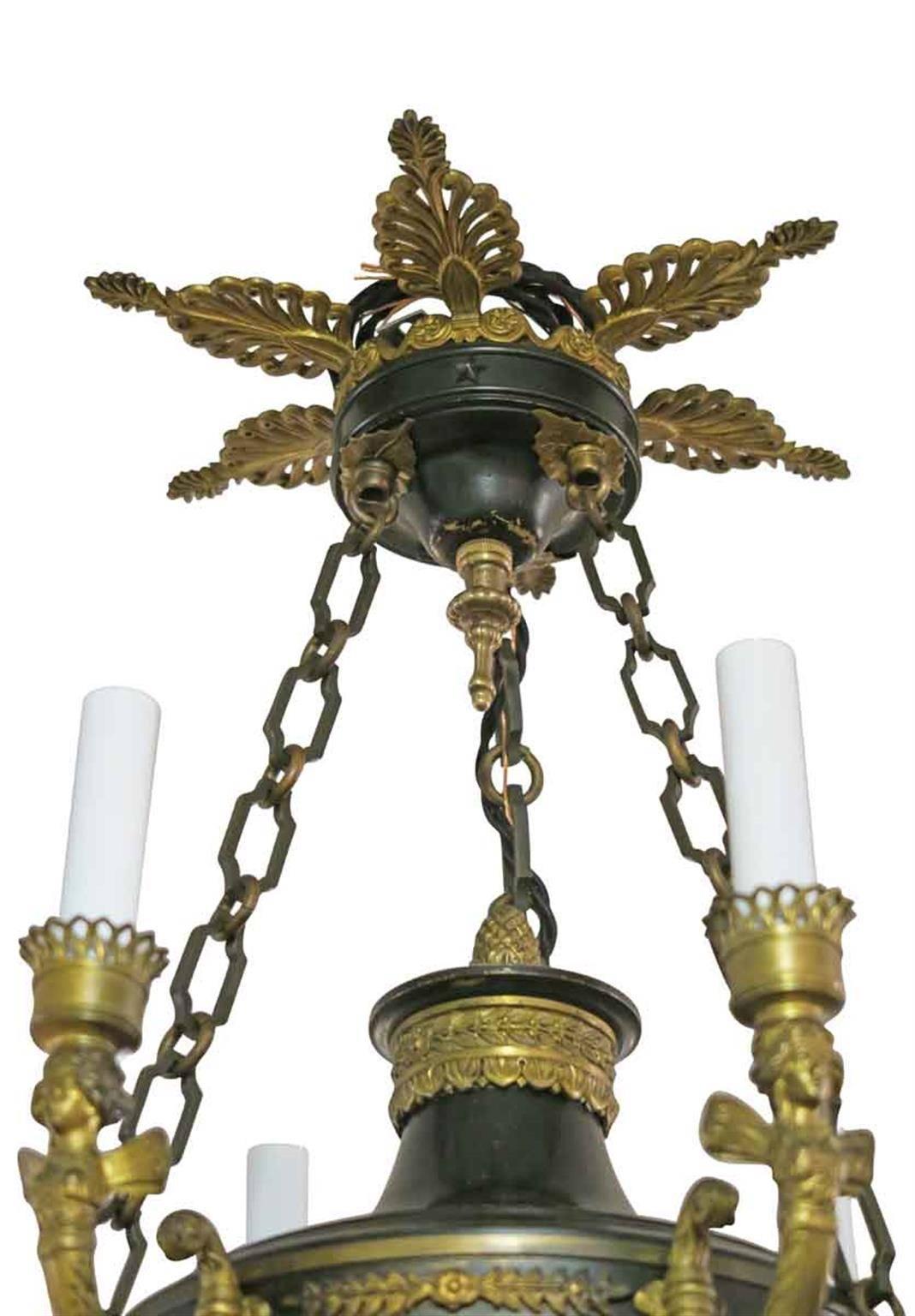 This French six-light chandelier is fashioned out of gilt bronze and is presented in an Empire style, circa 1900s. Arms come adorned with angels, bottom acorn finial. This can be seen at our 302 Bowery location in Manhattan.