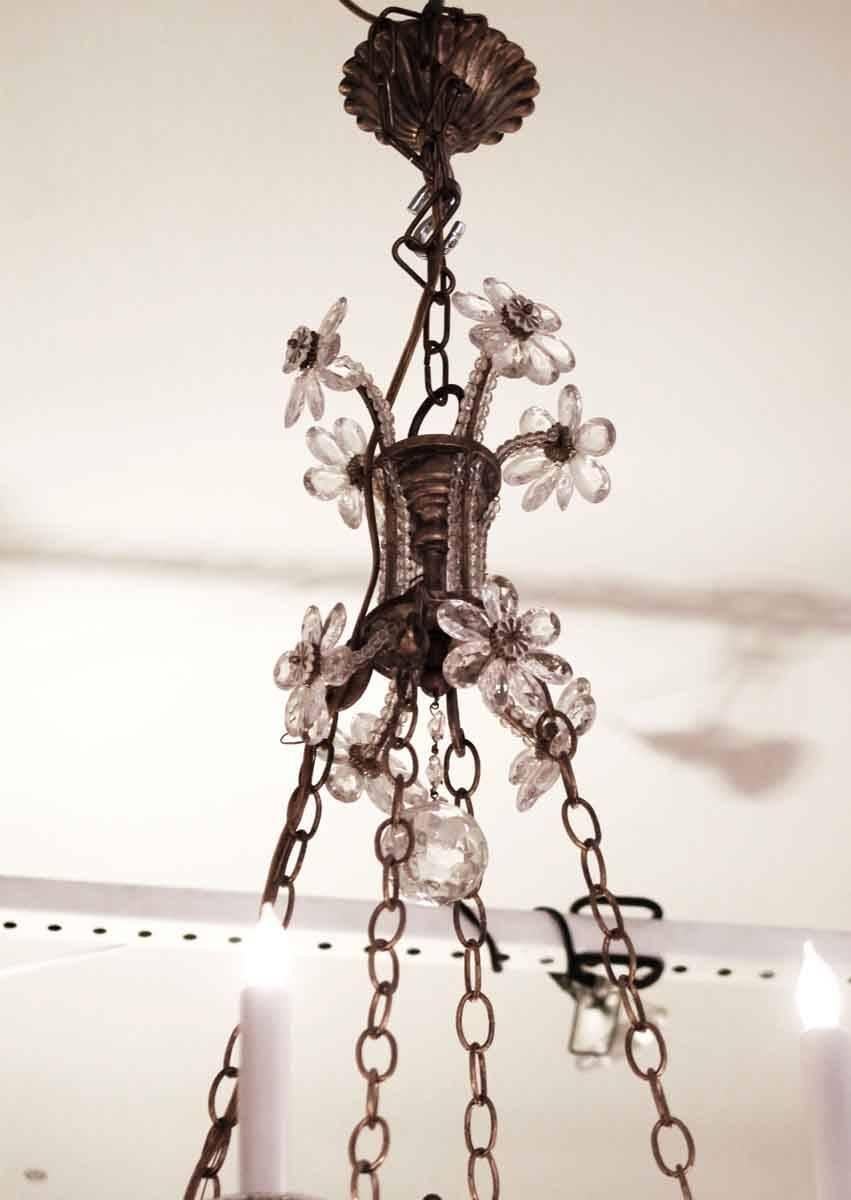 Wrought iron eight arm chandelier with a mirrored centerpiece, adorned with crystal flowers and leaves in a floral design and a crystal ball finial at bottom. This can be seen at our 302 Bowery location in NoHo in Manhattan.