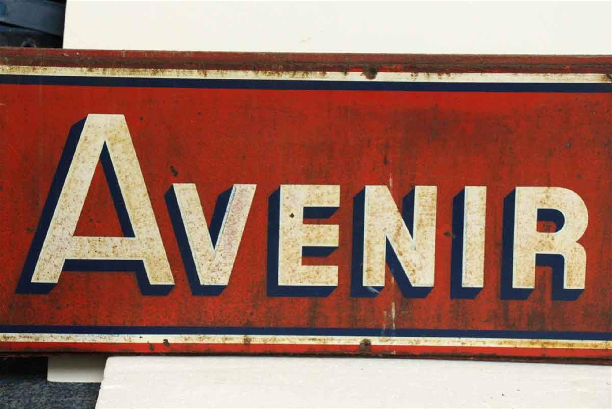 1960s French wood and metal sign reading 'Avenir Publicite'. This sign has a red background with white lettering. The English translation is 'Future Advertising'. This can be seen at our 149 Madison Ave location in Manhattan.