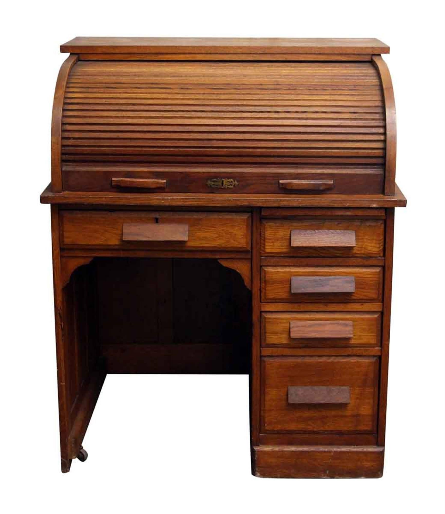 1920s solid oak roll top desk with recessed panels on the sides and back. Five drawers with wide solid oak handles. The front has a bronze keyhole escutcheon. Key is not included. This can be seen at our 2420 Broadway location on the upper west side