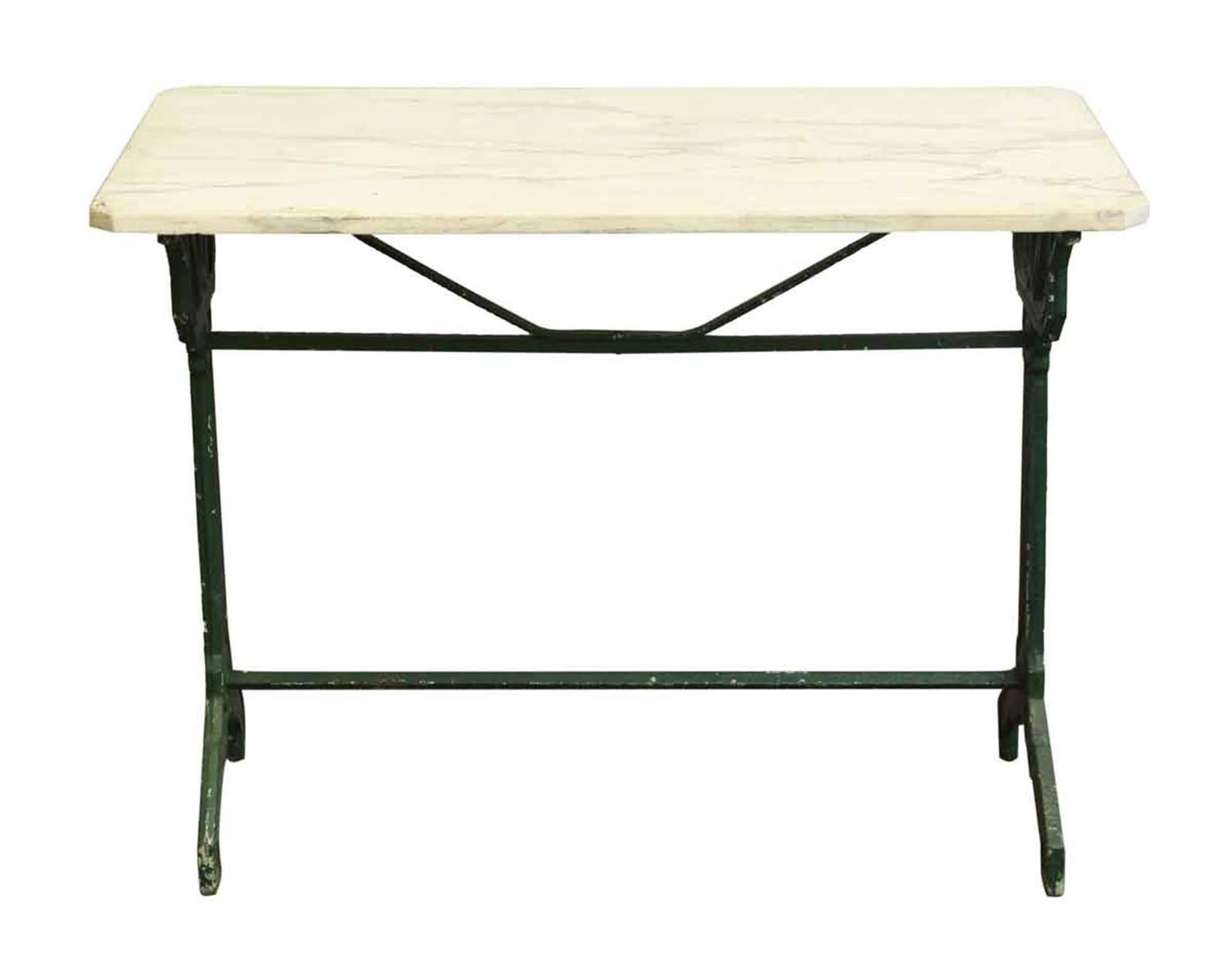 Green cast iron base table with a white veined marble top. The legs are inscribed Meubles Le Lion. This can be seen at our 302, Bowery location in Manhattan.