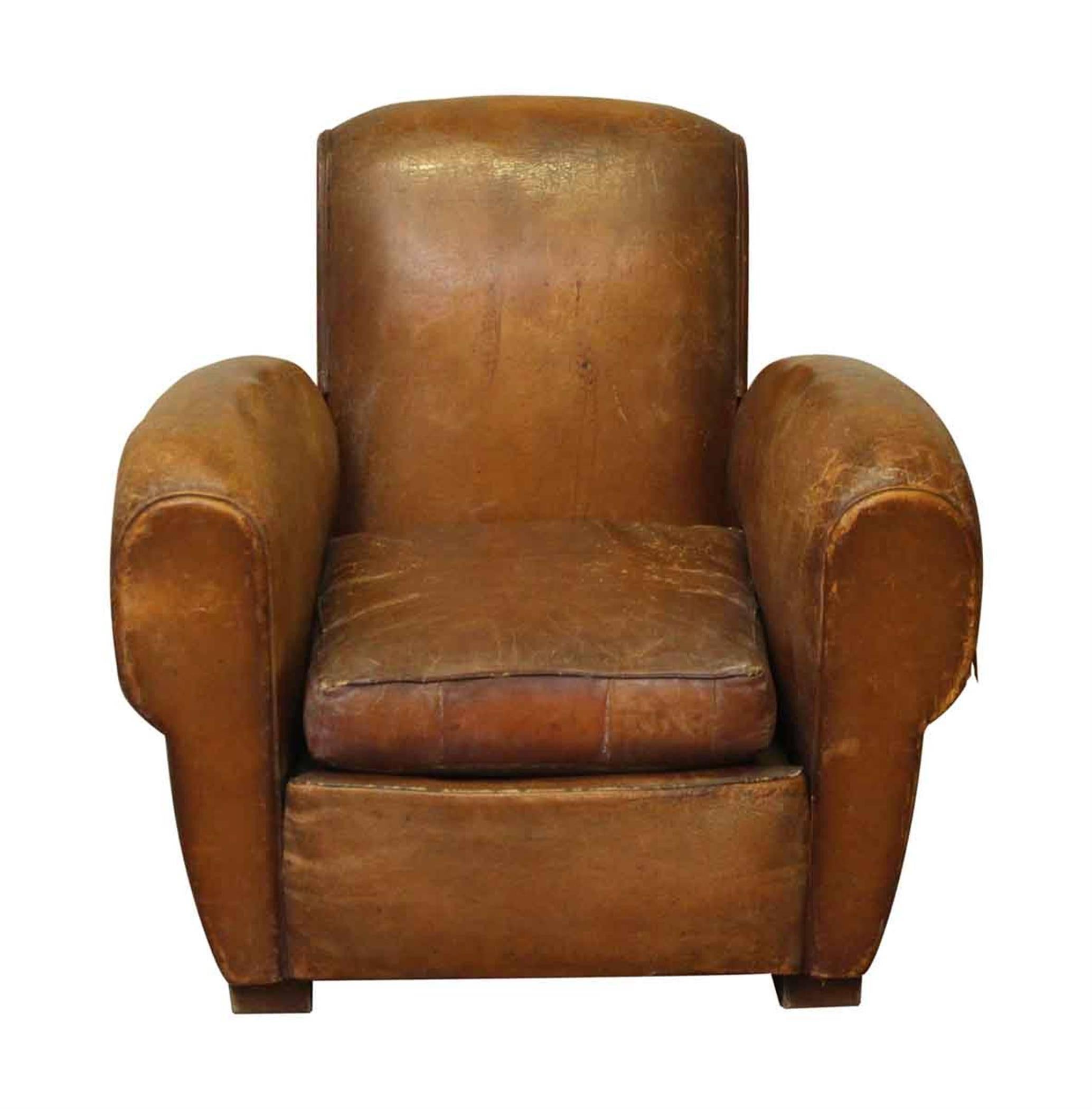 1970s French brown leather club chair with thick arms and studded detail on the back. There is some wear from age and use.