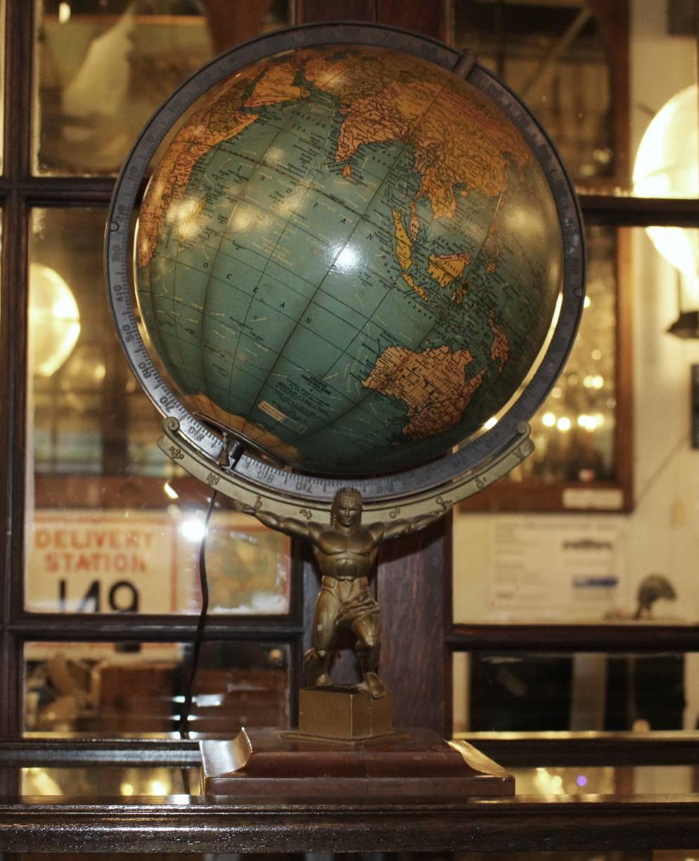 1949 Crams rare lit Art Deco style terrestrial table top globe made by The George F. Cram Co., Indianapolis, IN. Appears to be styled after statues found in Rockefeller Center. Lights up inside globe. This item can be viewed at our 149 Madison