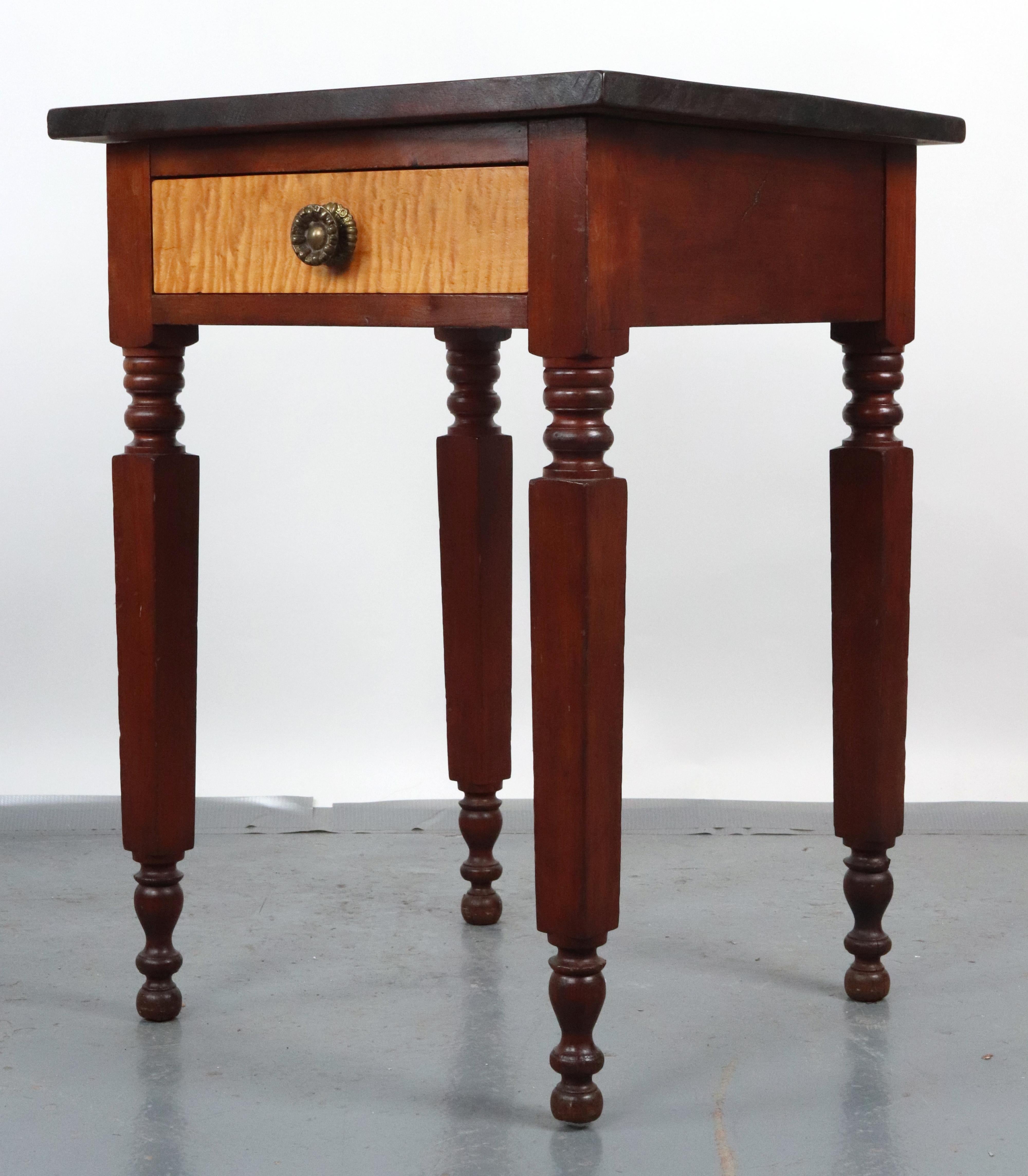 Sheraton style side table made of a pine tabletop, a maple drawer, and four cherry legs. The drawer was made using dovetail joints. It features a floral brass drawer knob. Good condition with surface wear and a crack in one leg toward the bottom.