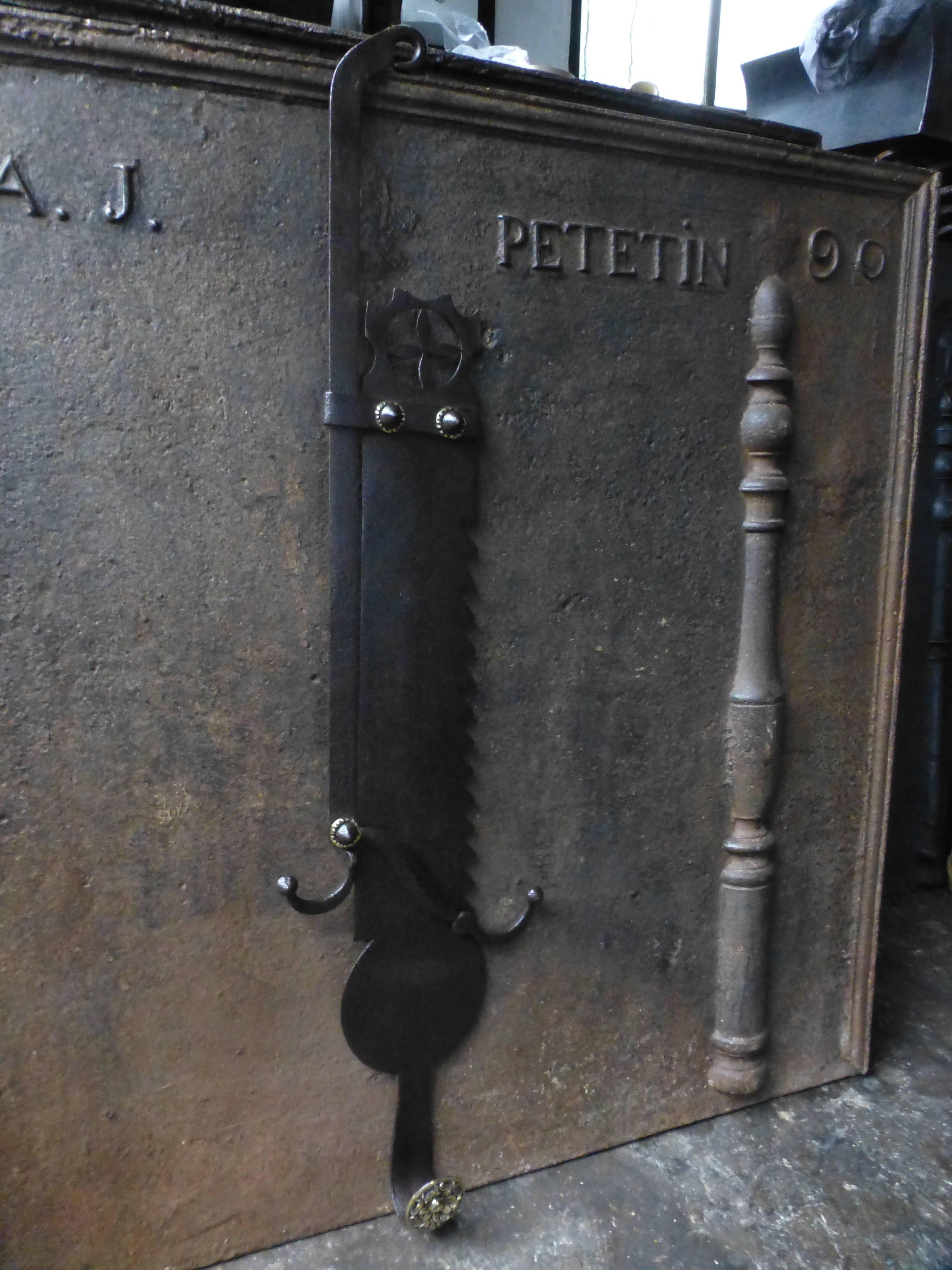 17th-18th century French fireplace trammel made of wrought iron and polished brass. 

The trammel was used for cooking to regulate the distance between pot and fire. The height is the length of the saw.