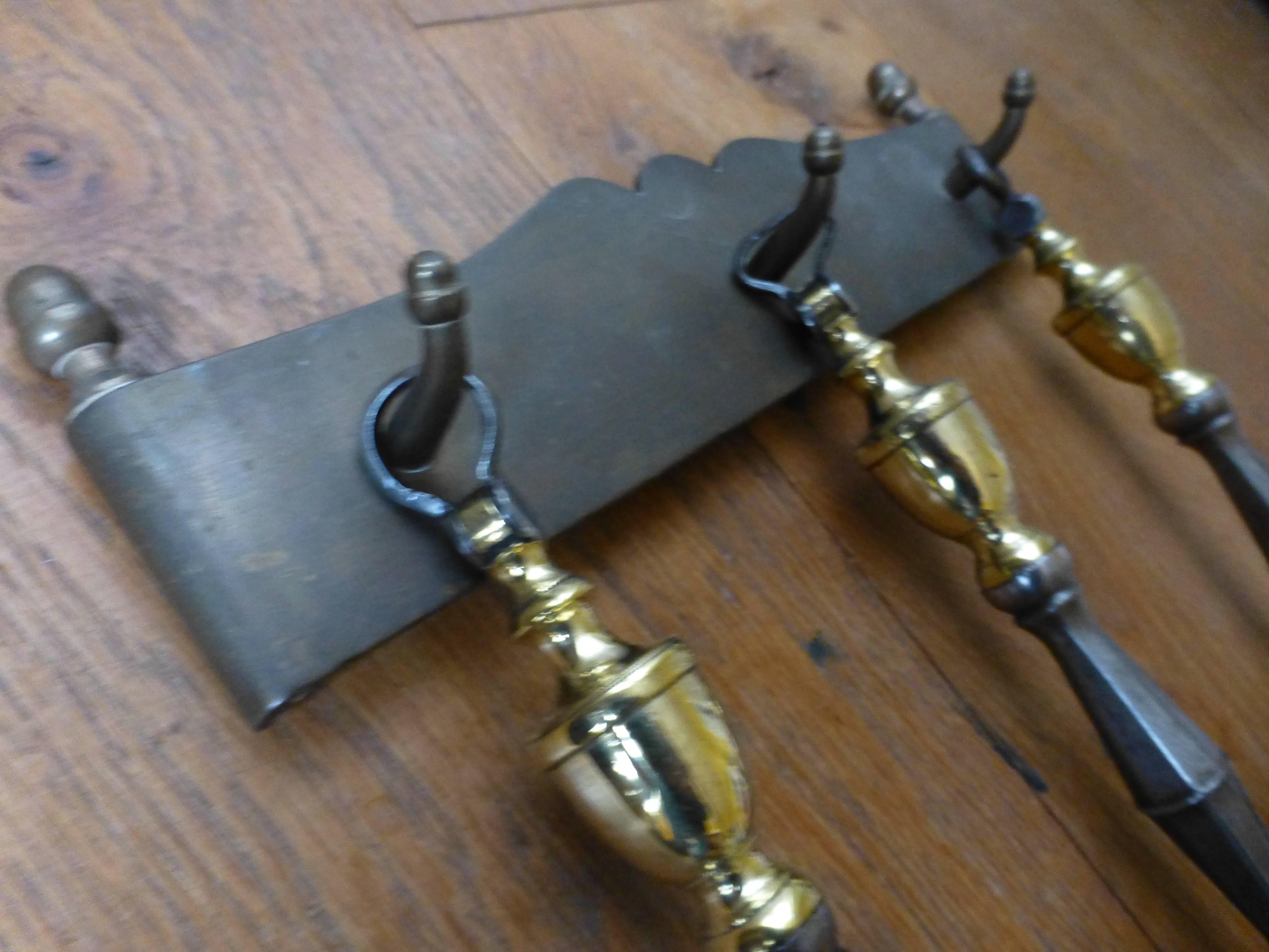 Set of 19th century English fireplace tools. The hanger is made of brass and the tools are made of polished steel and polished brass.