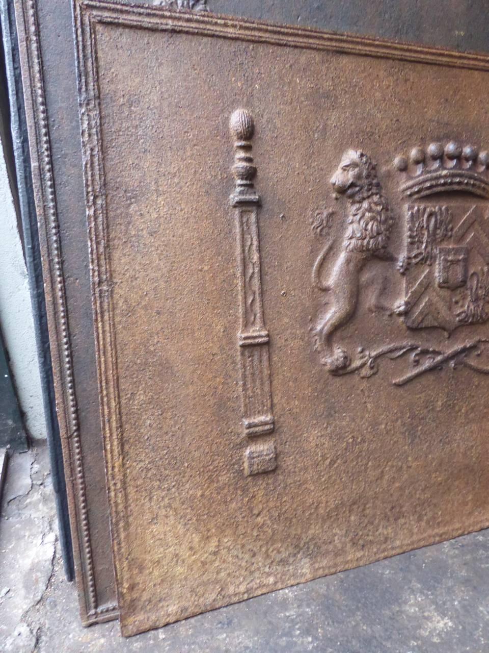19th century French fireback with a coat of arms and two pillars.

The style of the fireback is neoclassical as shown by the pillars. The fireback was produced in that style period. But the coat of arms is definitely from a style period prior to