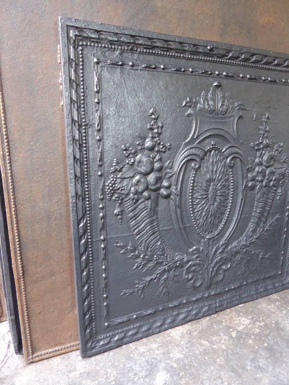 18th century French fireback with two horns of plenty, a sunflower and other greenery.