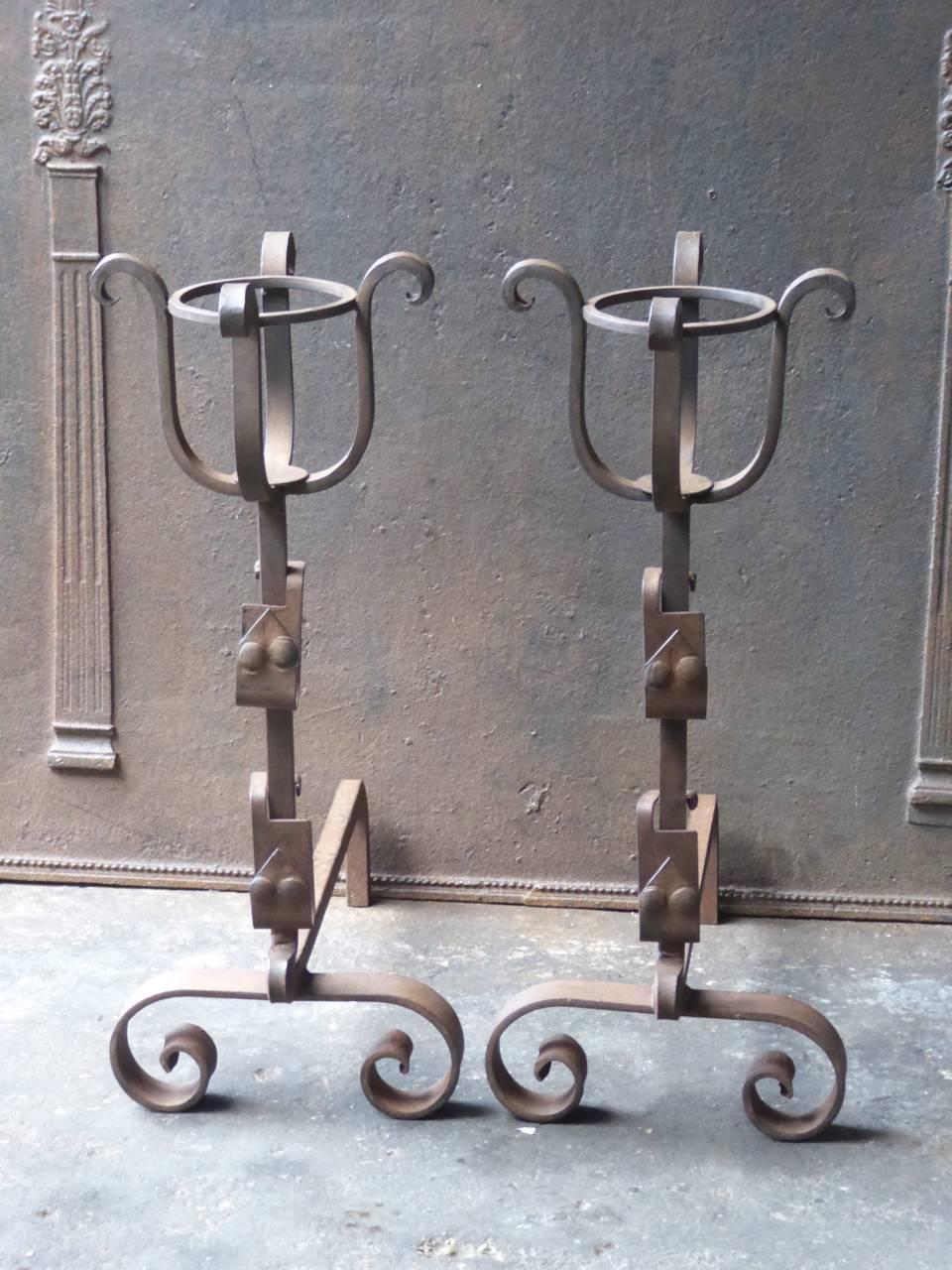 French wrought iron andirons with spit hooks to grill food and a cup to keep drinks or soup warm. The style is Napoleon III. 20th century.
