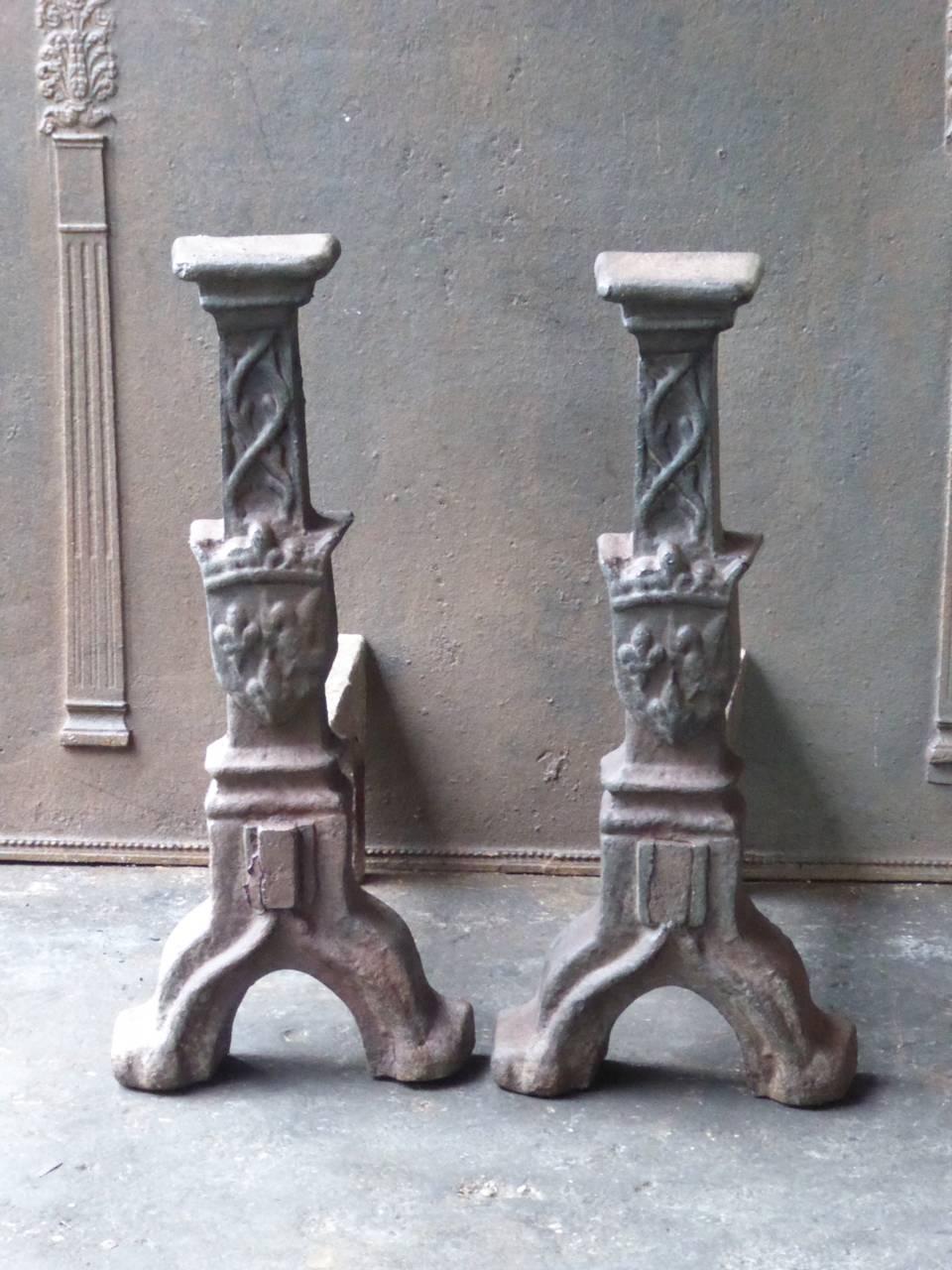 Early 20th century French Louis XIII style firedogs made of cast iron. The firedogs have a crown (symbol for royalty) and three fleurs-de-lys (symbol for aristocracy throughout Europe and stand for purity).