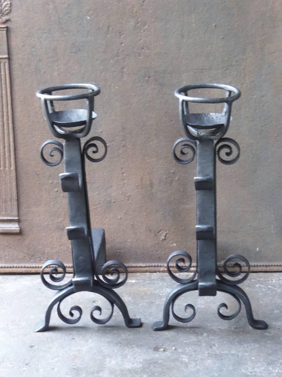 French andirons made of wrought iron. With spit hooks to grill food and a cup to keep drinks or soup warm.