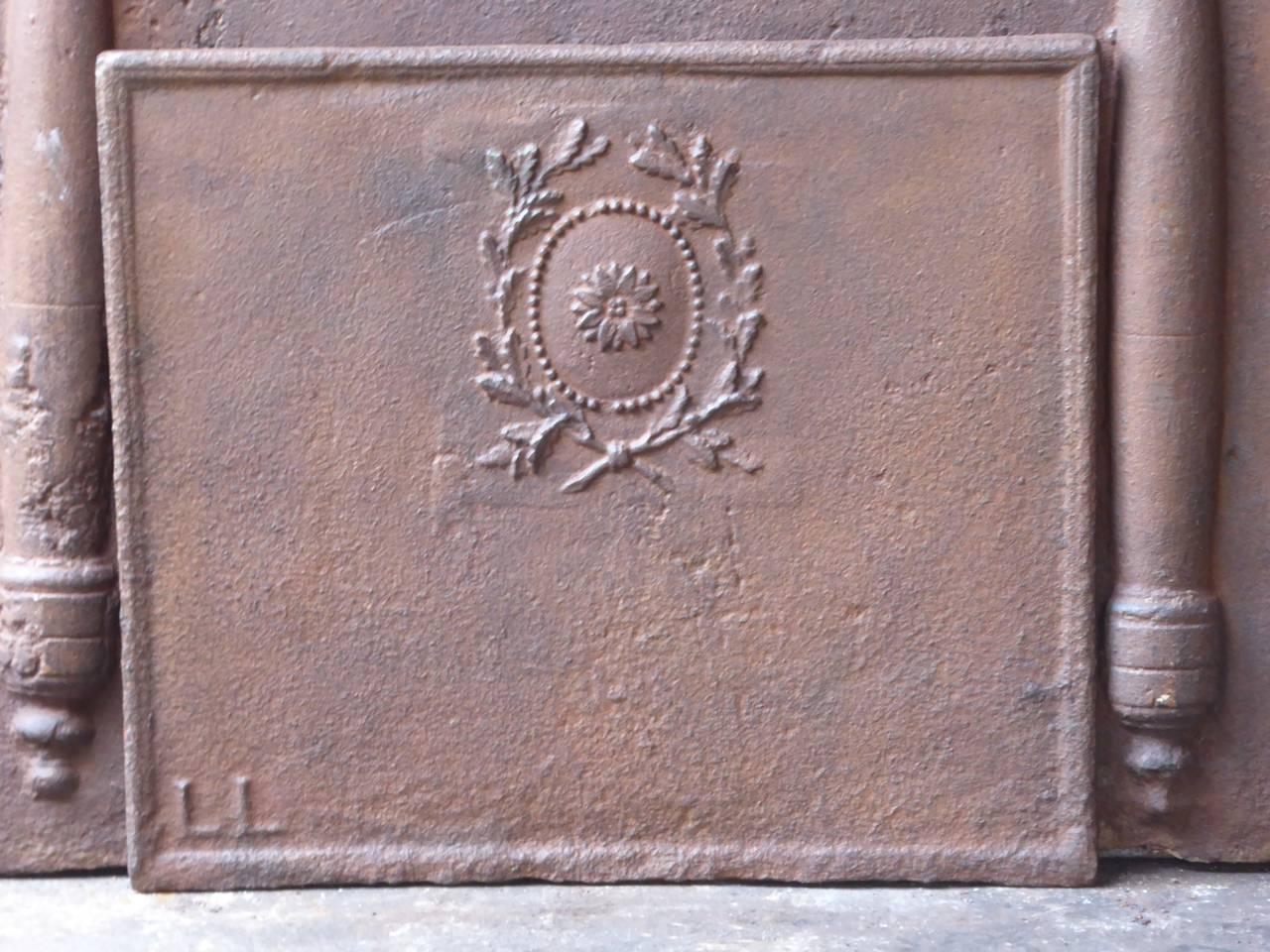 19th century French fireback with a decoration, including an olive wreath. The olive branches symbolize peace and victory. In the left corner, the initials L.L. are cast.

We have a unique and specialized collection of antique and used fireplace