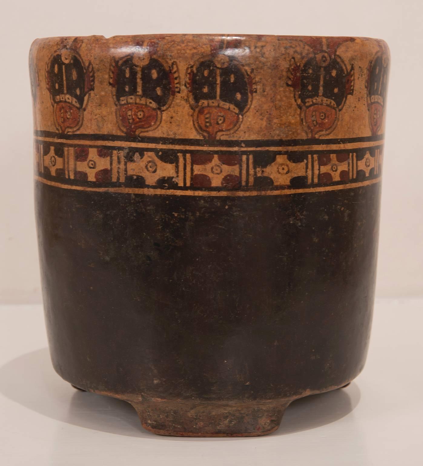 Pre-Columbian, Honduras, Ulua Valley, polychromed pottery cylinder standing on lug type tripot feet, painted in shades of red, orange and black. Upper bar features a repeating series of zoomorphic figures.